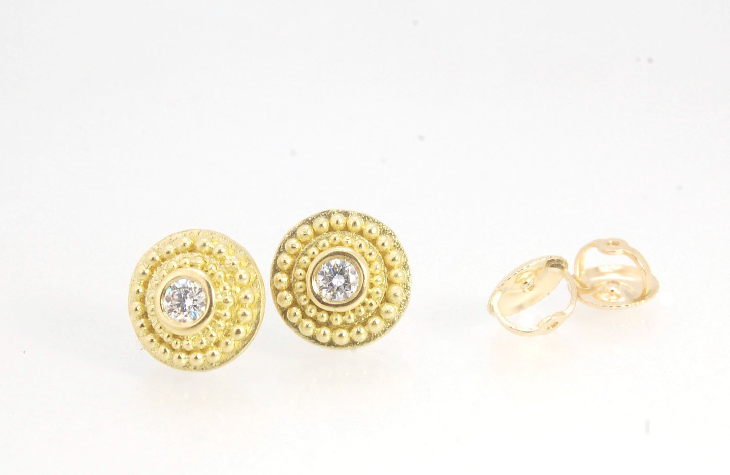 Diamond Disc Post Earrings - 18k Gold Granulation with 14k screw backs These Diamond Disc Stud Earrings are Classically-inspired 18k granulation. With 2 ethically-mined, .10ct , 3mm, Sl1, F+ round diamonds bezel-set in 18k a double ring of 18k gold granul
