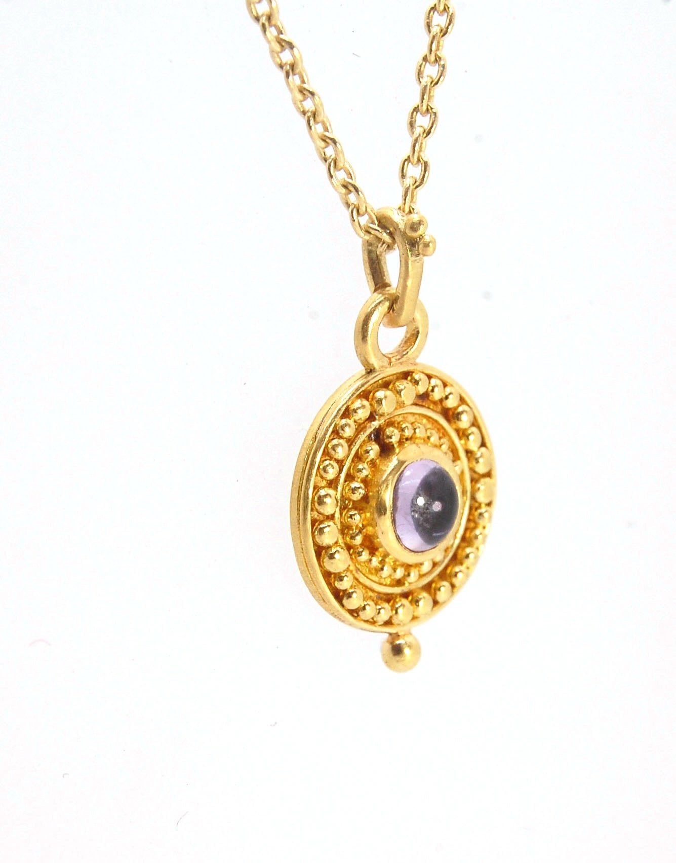 Amethyst 18k Gold Granulation Medallion This lovely light amethyst cabochon is surrounded by the 18k gold bezel setting and 18k gold granulation with a notched granulated bail. This classically inspired medallion looks like it could have come from buried