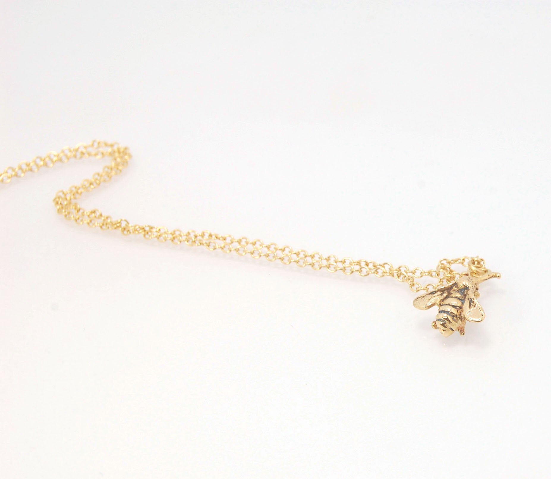 Bee Pendant in 14k gold These bees were so fun to carve!Carved in wax and cast using a lost-wax process in 14k gold. I finish the bee with a dark patina in the recess and attach an oxidized sterling chain length of your specification. I then give the bee