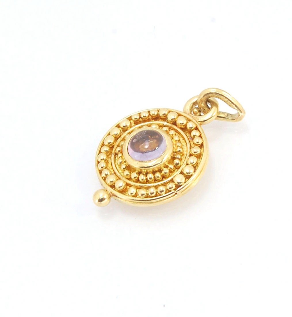 Amethyst 18k Gold Granulation Medallion This lovely light amethyst cabochon is surrounded by the 18k gold bezel setting and 18k gold granulation with a notched granulated bail. This classically inspired medallion looks like it could have come from buried