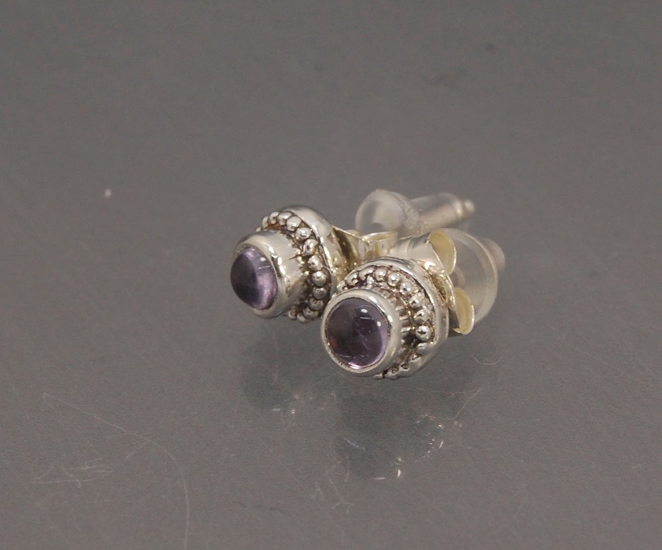 Amethyst Tiny Post Earrings in Sterling Silver These are tiny bezel settings I created using the ancient process of granulation. I then made a mold of it and injected the mold with wax and used that wax to create a Sterling Silver version of these granula