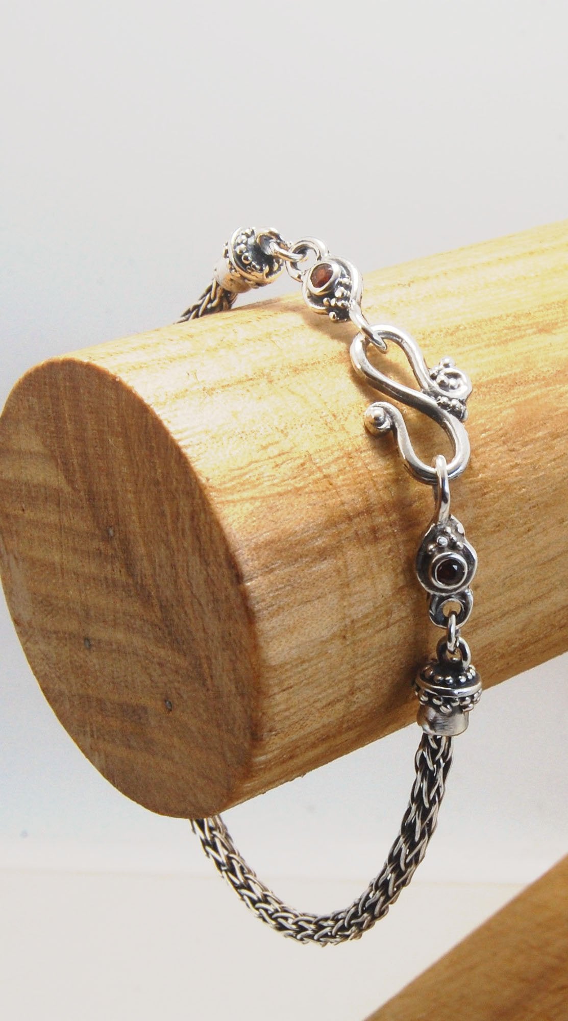 Garnet Wisteria Viking Knit Woven Silver Bracelet These woven bracelets are hand-woven in Viking knit style from fine silver with a cast granulated cap, garnet set Wisteria settings and a sterling S clasp. This chain takes many hours to make. The original
