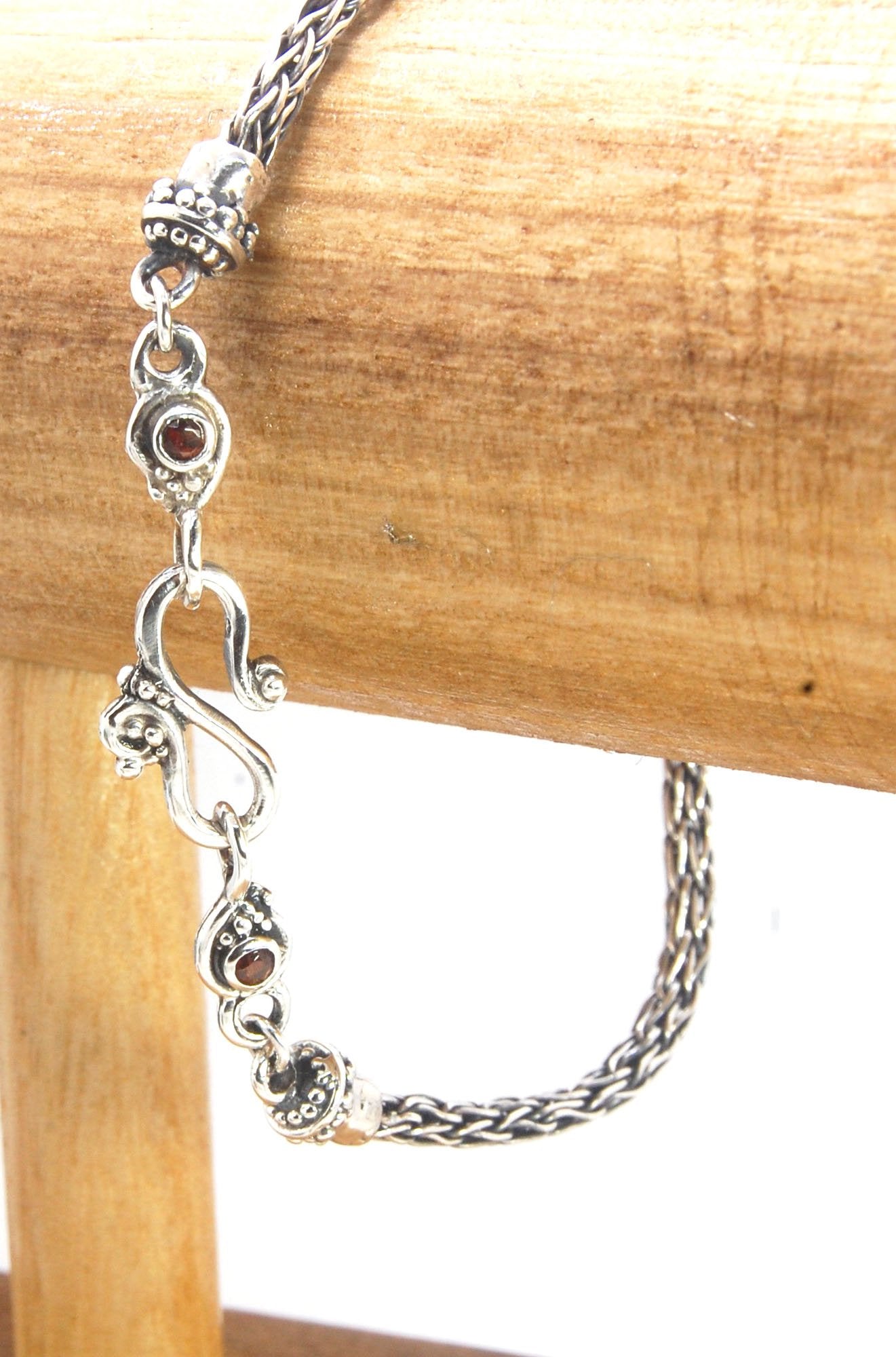 Garnet Wisteria Viking Knit Woven Silver Bracelet These woven bracelets are hand-woven in Viking knit style from fine silver with a cast granulated cap, garnet set Wisteria settings and a sterling S clasp. This chain takes many hours to make. The original