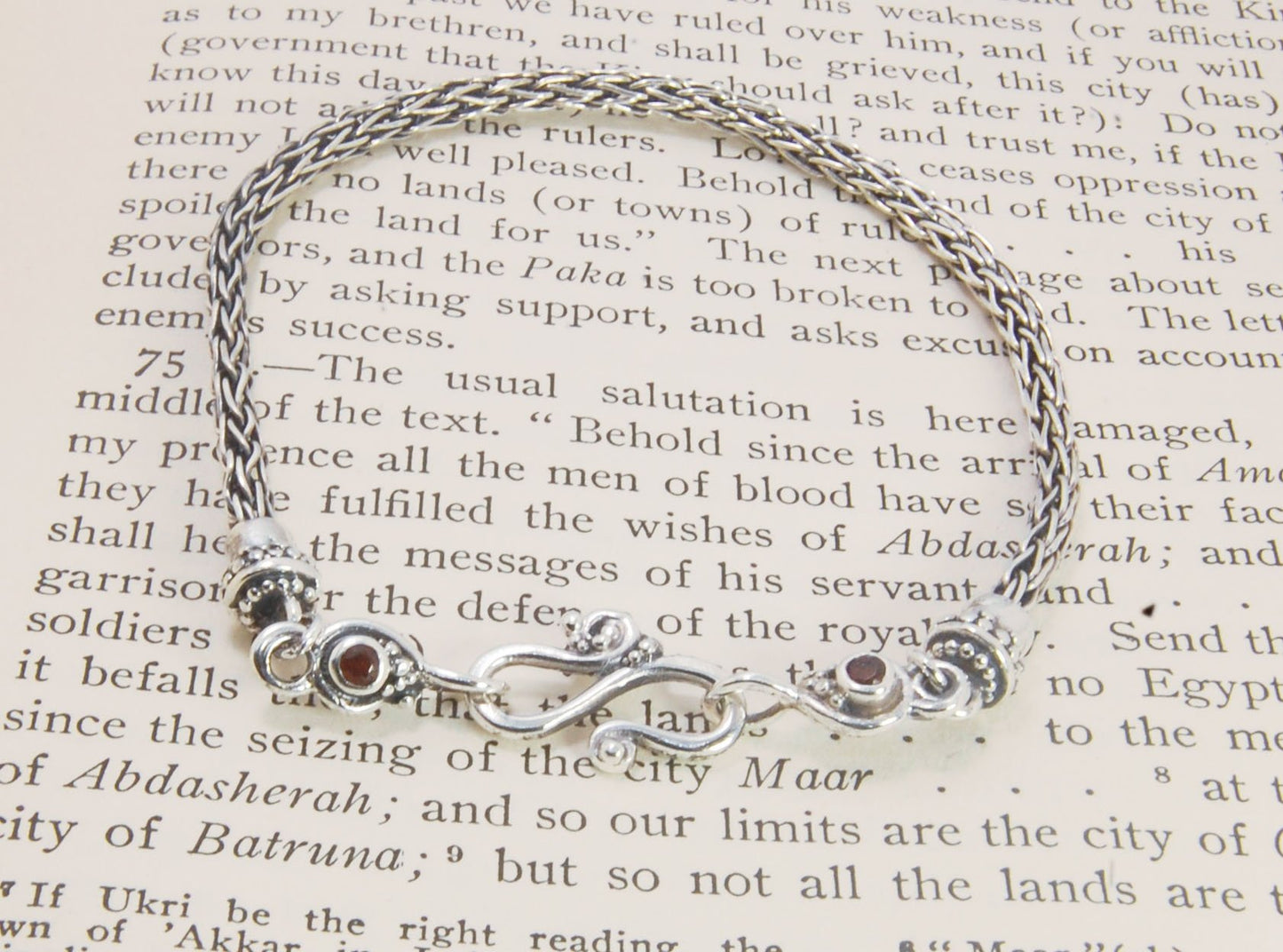 Garnet Wisteria Viking Knit Woven Silver Bracelet These woven bracelets are hand-woven in Viking knit style from fine silver with a cast granulated cap, garnet set Wisteria settings and a sterling S clasp. This chain takes many hours to make. The original