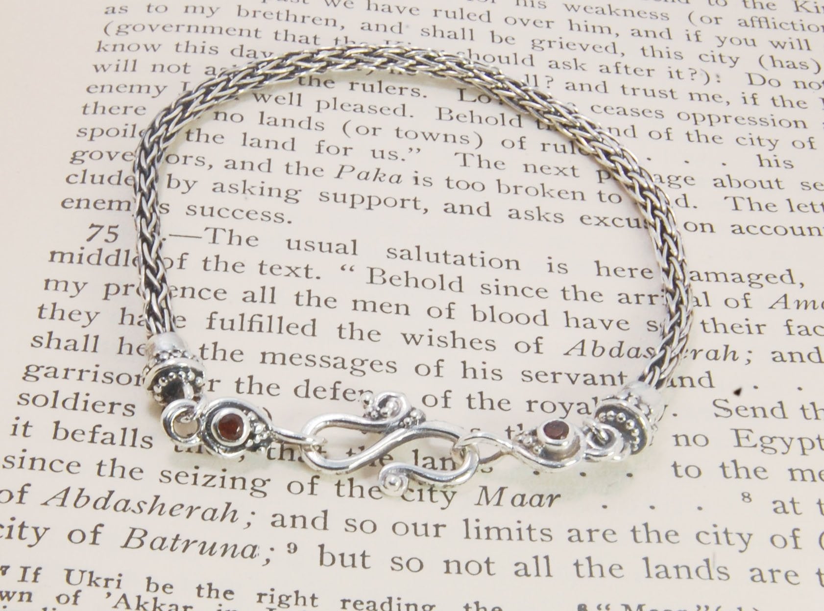 Garnet Wisteria Viking Knit Woven Silver Bracelet These woven bracelets are hand-woven in Viking knit style from fine silver with a cast granulated cap, garnet set Wisteria settings and a sterling S clasp. This chain takes many hours to make. The original