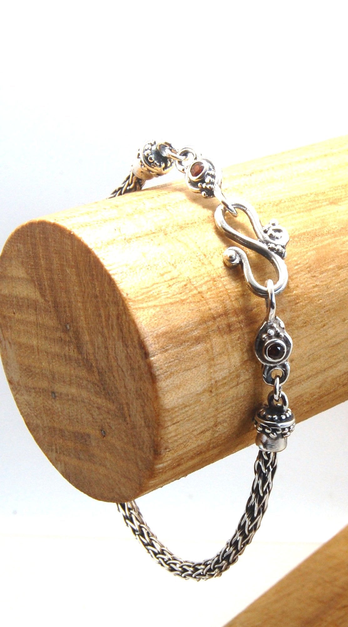 Garnet Wisteria Viking Knit Woven Silver Bracelet These woven bracelets are hand-woven in Viking knit style from fine silver with a cast granulated cap, garnet set Wisteria settings and a sterling S clasp. This chain takes many hours to make. The original