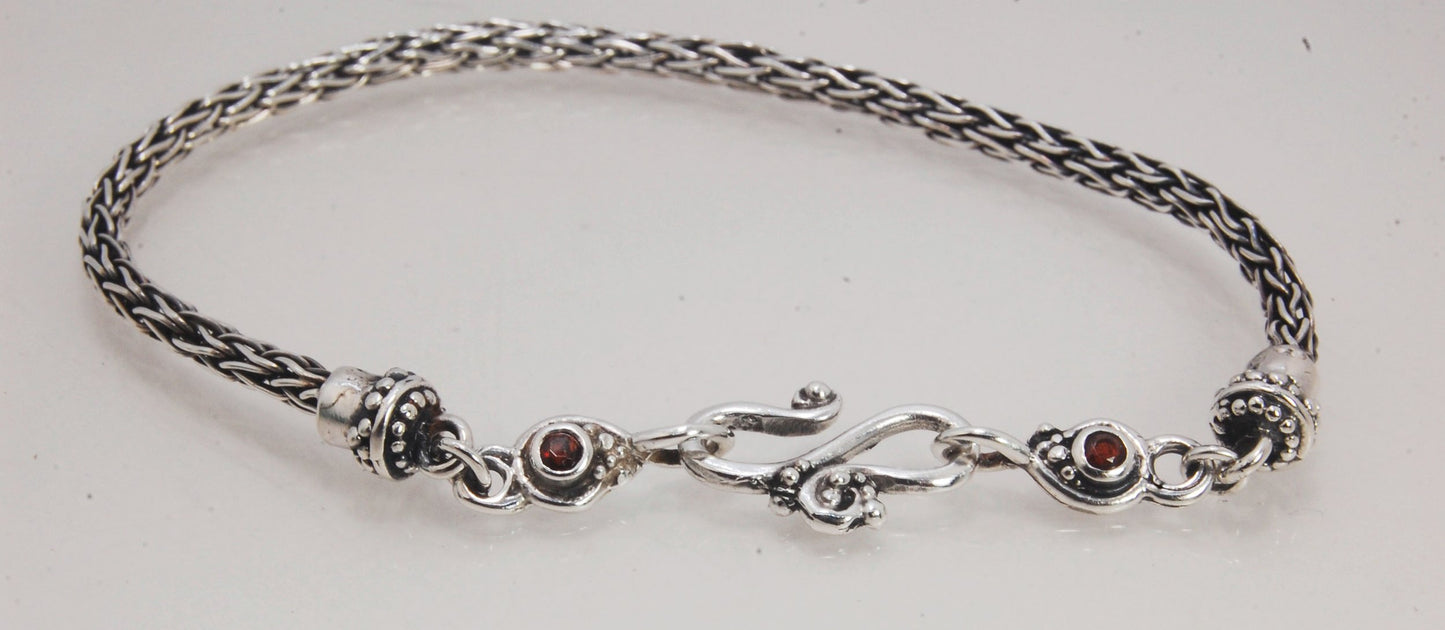 Garnet Wisteria Viking Knit Woven Silver Bracelet These woven bracelets are hand-woven in Viking knit style from fine silver with a cast granulated cap, garnet set Wisteria settings and a sterling S clasp. This chain takes many hours to make. The original
