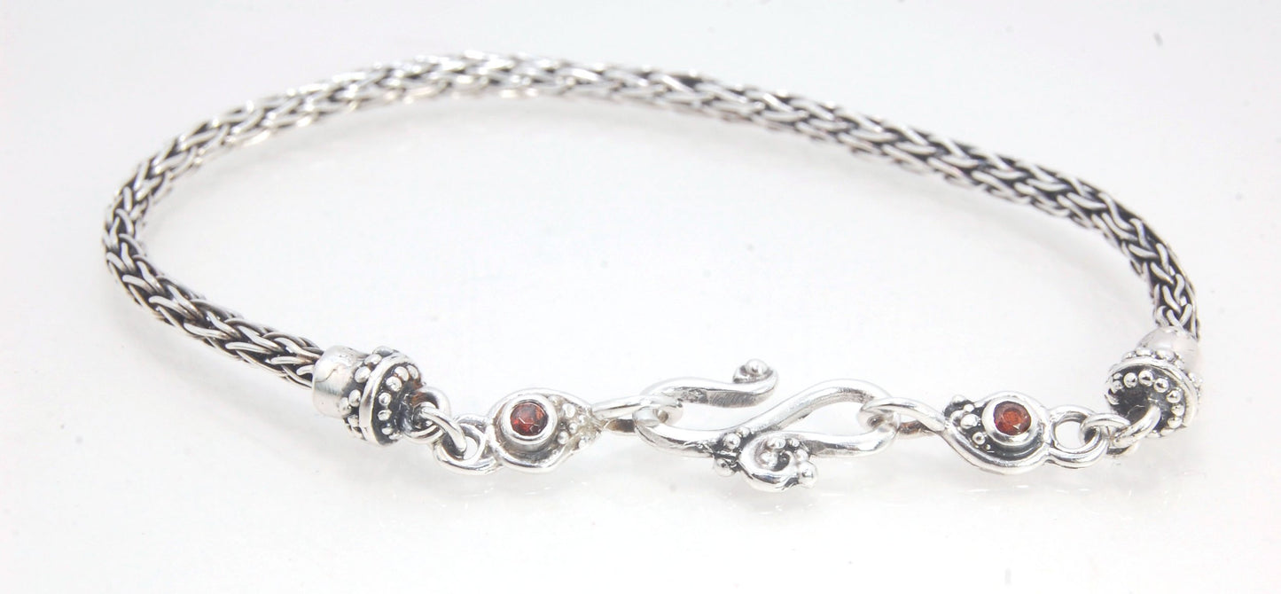 Garnet Wisteria Viking Knit Woven Silver Bracelet These woven bracelets are hand-woven in Viking knit style from fine silver with a cast granulated cap, garnet set Wisteria settings and a sterling S clasp. This chain takes many hours to make. The original