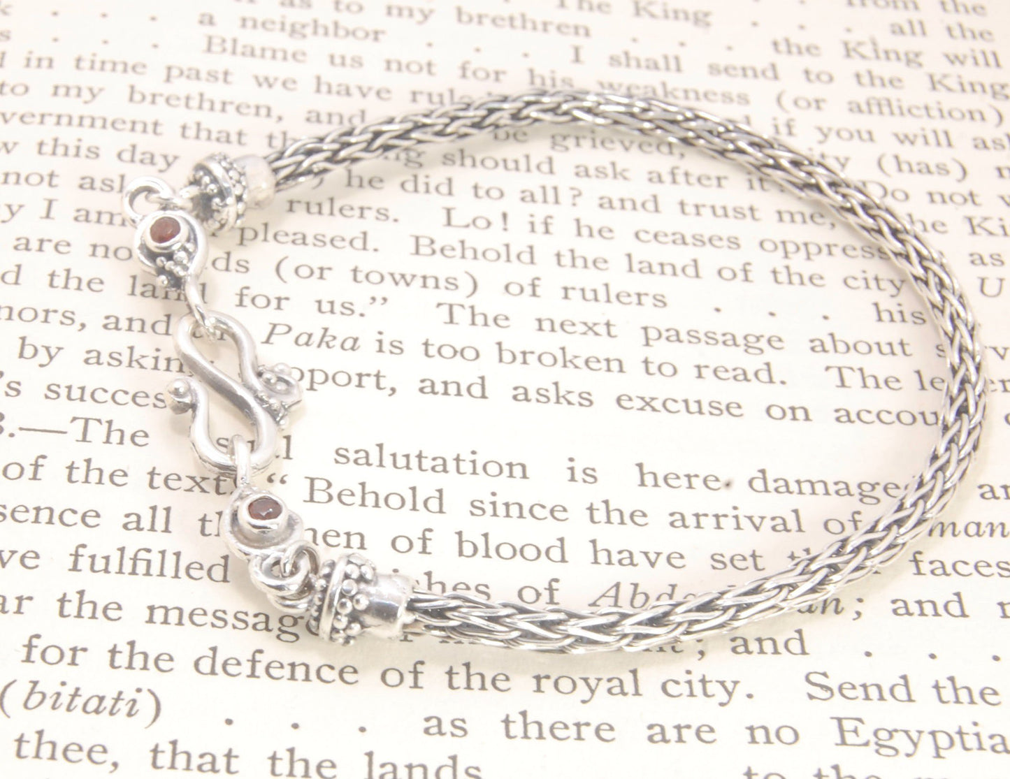 Garnet Wisteria Viking Knit Woven Silver Bracelet These woven bracelets are hand-woven in Viking knit style from fine silver with a cast granulated cap, garnet set Wisteria settings and a sterling S clasp. This chain takes many hours to make. The original