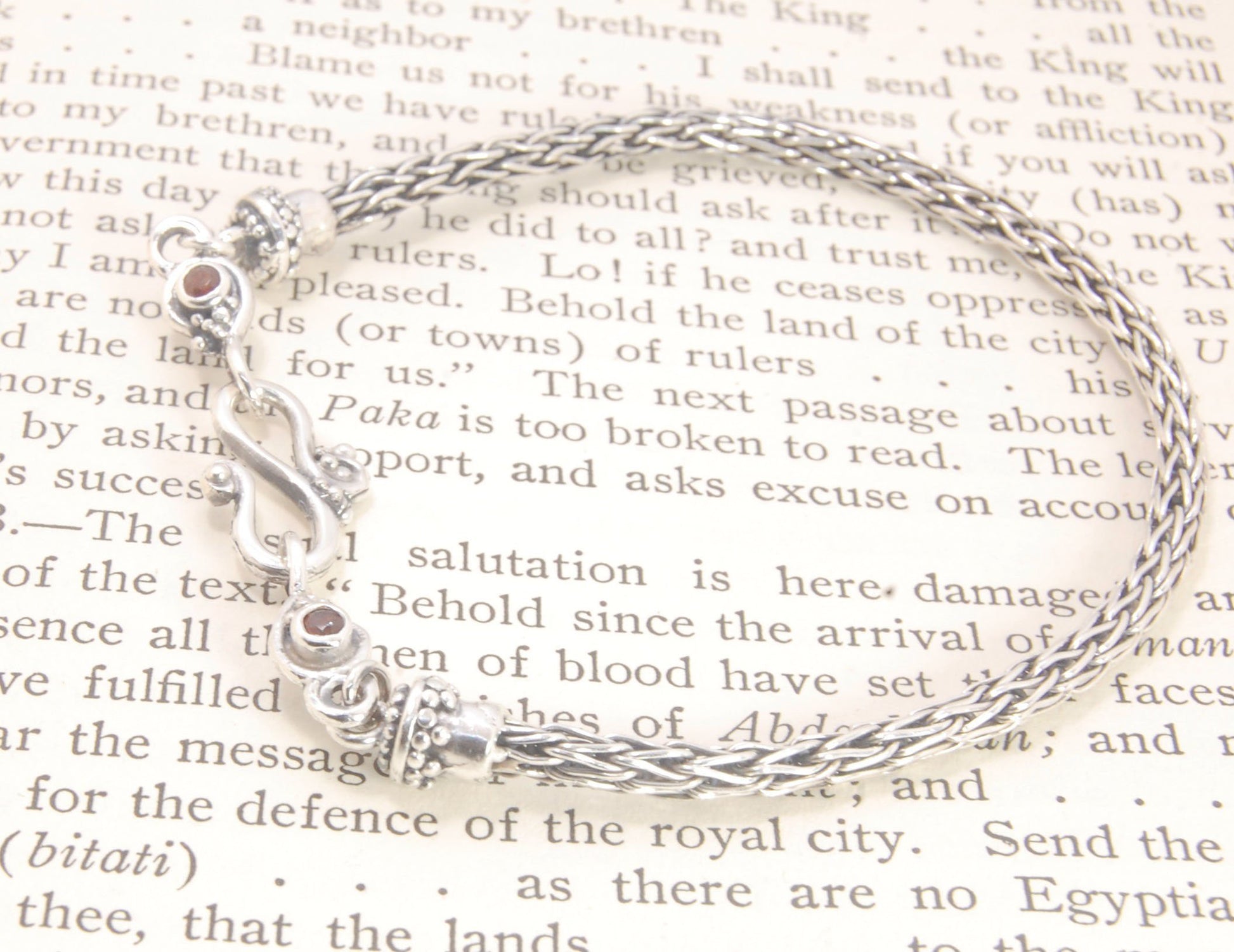 Garnet Wisteria Viking Knit Woven Silver Bracelet These woven bracelets are hand-woven in Viking knit style from fine silver with a cast granulated cap, garnet set Wisteria settings and a sterling S clasp. This chain takes many hours to make. The original