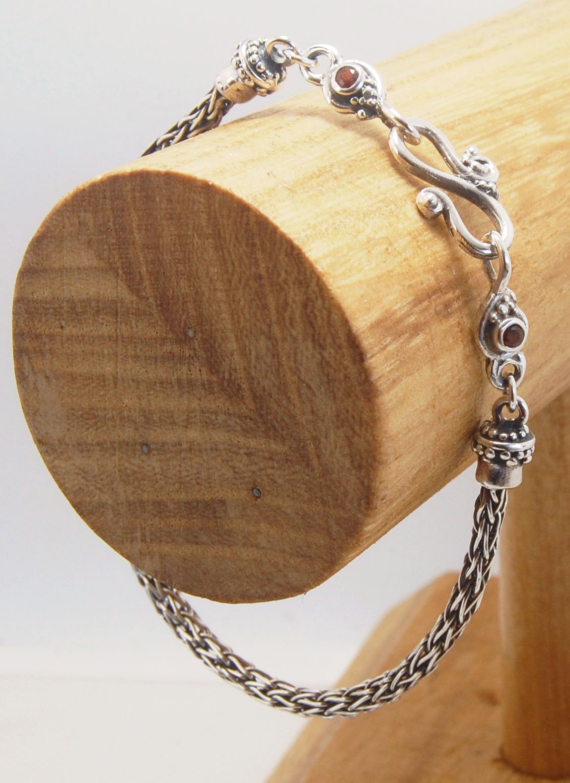 Garnet Wisteria Viking Knit Woven Silver Bracelet These woven bracelets are hand-woven in Viking knit style from fine silver with a cast granulated cap, garnet set Wisteria settings and a sterling S clasp. This chain takes many hours to make. The original