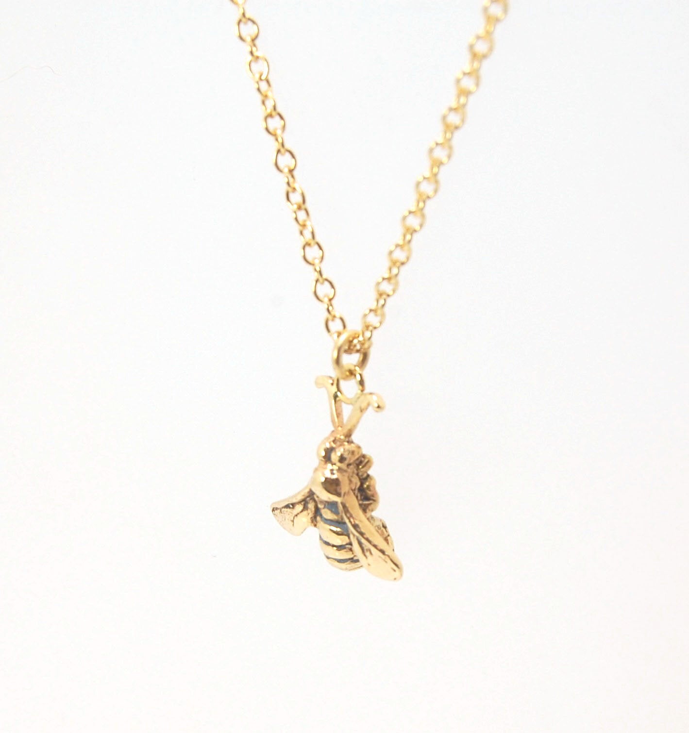 Bee Pendant in 14k gold These bees were so fun to carve!Carved in wax and cast using a lost-wax process in 14k gold. I finish the bee with a dark patina in the recess and attach an oxidized sterling chain length of your specification. I then give the bee