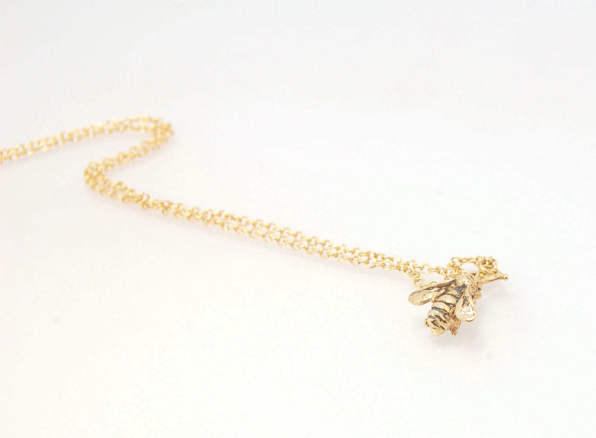 Bee Pendant in 14k gold These bees were so fun to carve!Carved in wax and cast using a lost-wax process in 14k gold. I finish the bee with a dark patina in the recess and attach an oxidized sterling chain length of your specification. I then give the bee