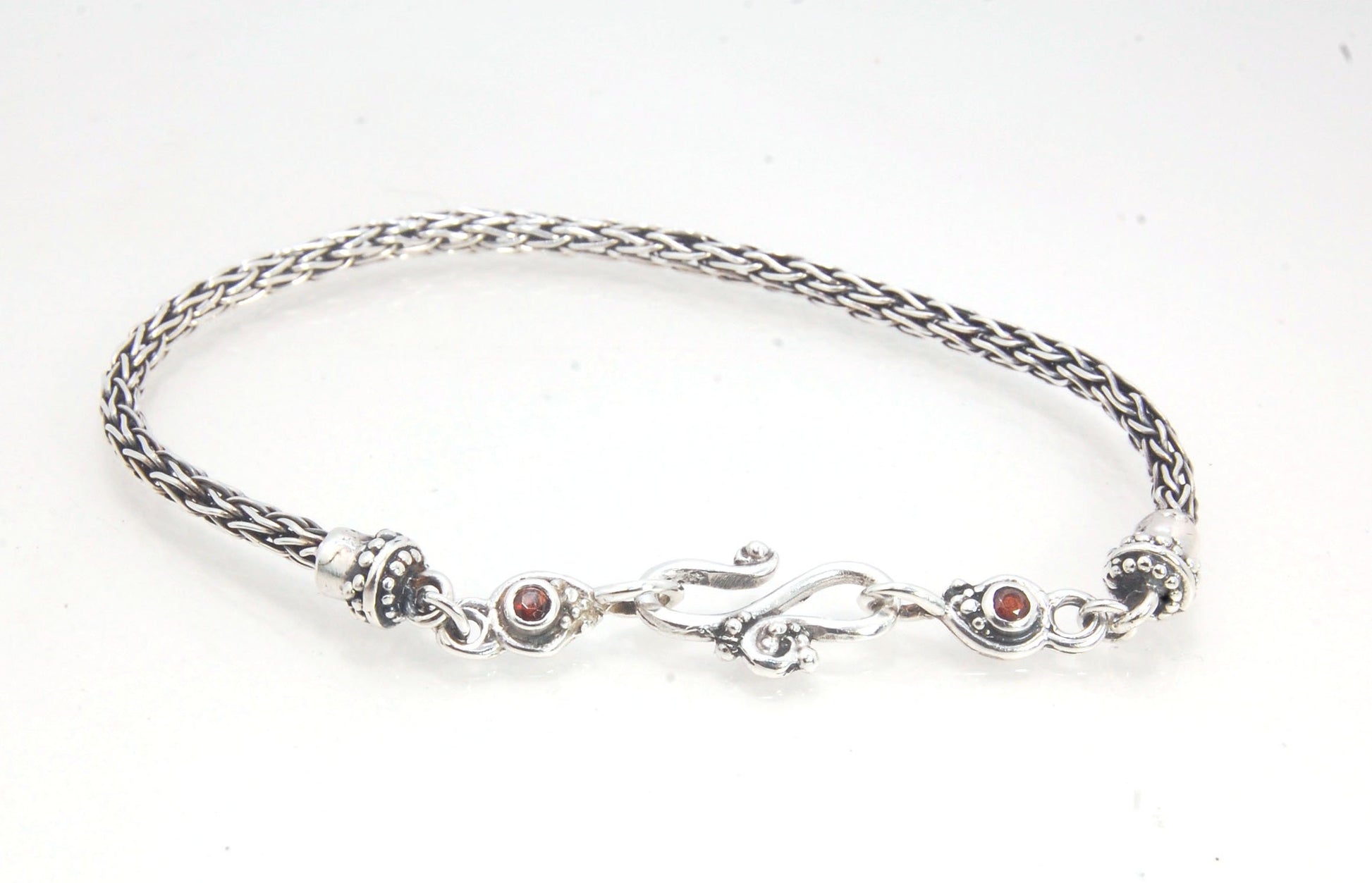 Garnet Wisteria Viking Knit Woven Silver Bracelet These woven bracelets are hand-woven in Viking knit style from fine silver with a cast granulated cap, garnet set Wisteria settings and a sterling S clasp. This chain takes many hours to make. The original