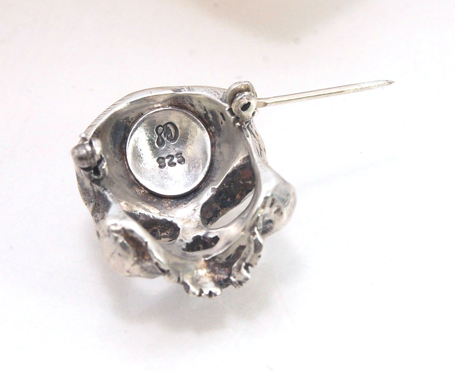 Through the Veil Darkly Skull Face Pin This Through the Veil Darkly Skull Face pin in Sterling Silver has a lot of expression and a nice weight with a hinged pin stem and clasp. It’s not too big or too small or too heavy. It will look great on your sweate