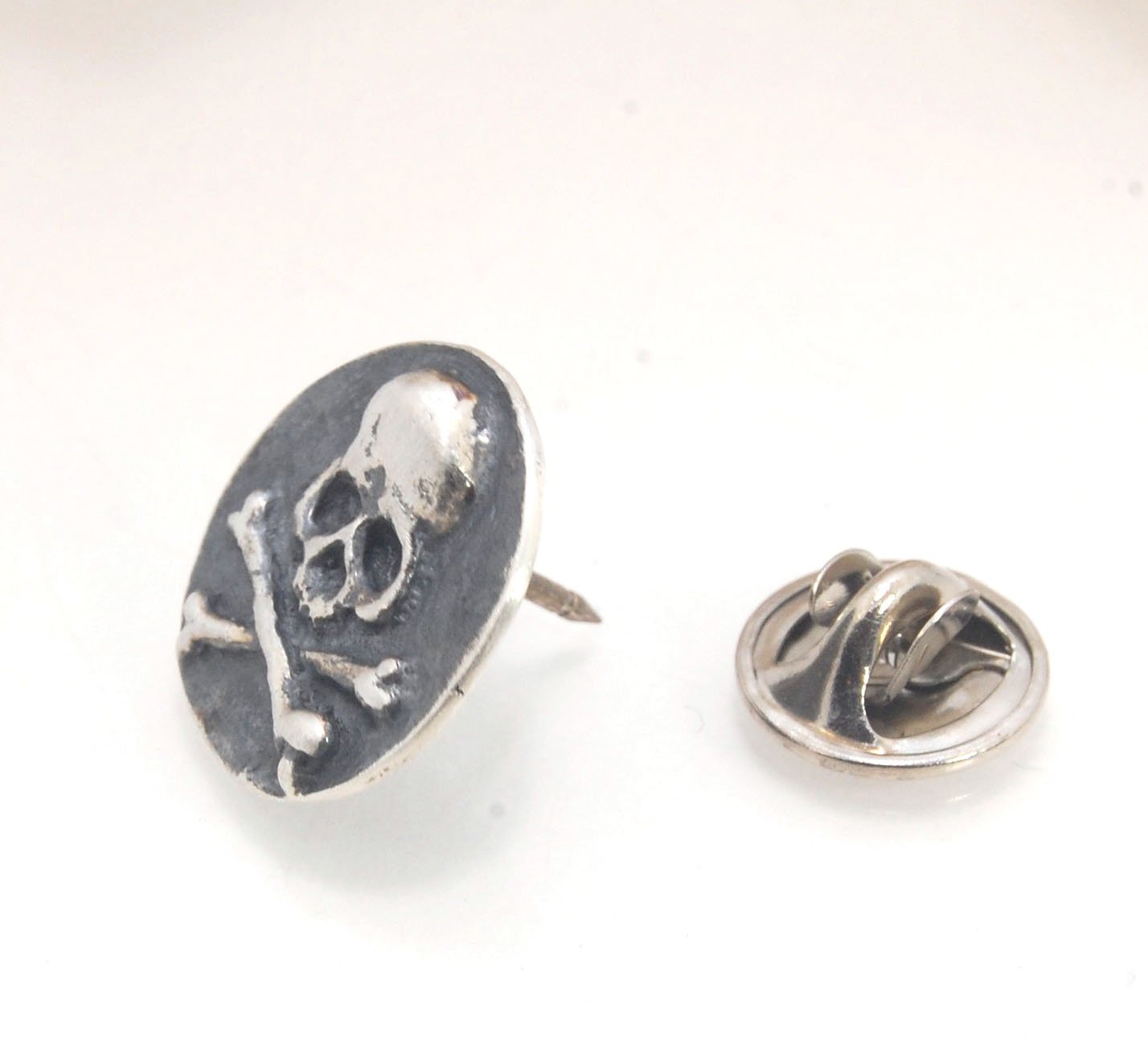 Skullbones Coin Lapel Pin These solid sterling silver SkullBones Coin Lapel Pin can also be worn as a Tie Tack. This Skullbones Coin is wax carved by hand and cast using the ancient process of Lost Wax to cast them in sterling silver. I then made a mold,