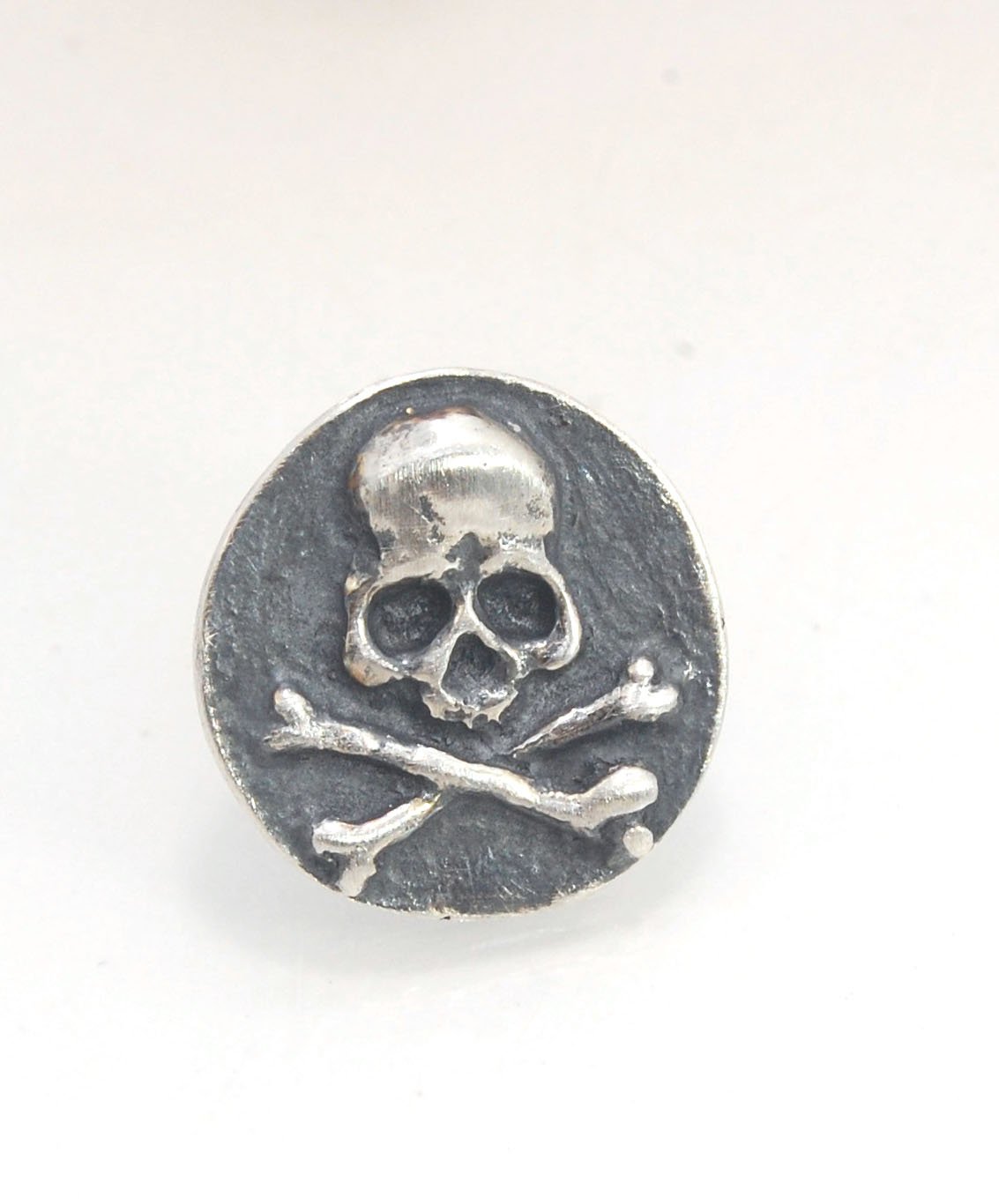Skullbones Coin Lapel Pin These solid sterling silver SkullBones Coin Lapel Pin can also be worn as a Tie Tack. This Skullbones Coin is wax carved by hand and cast using the ancient process of Lost Wax to cast them in sterling silver. I then made a mold,