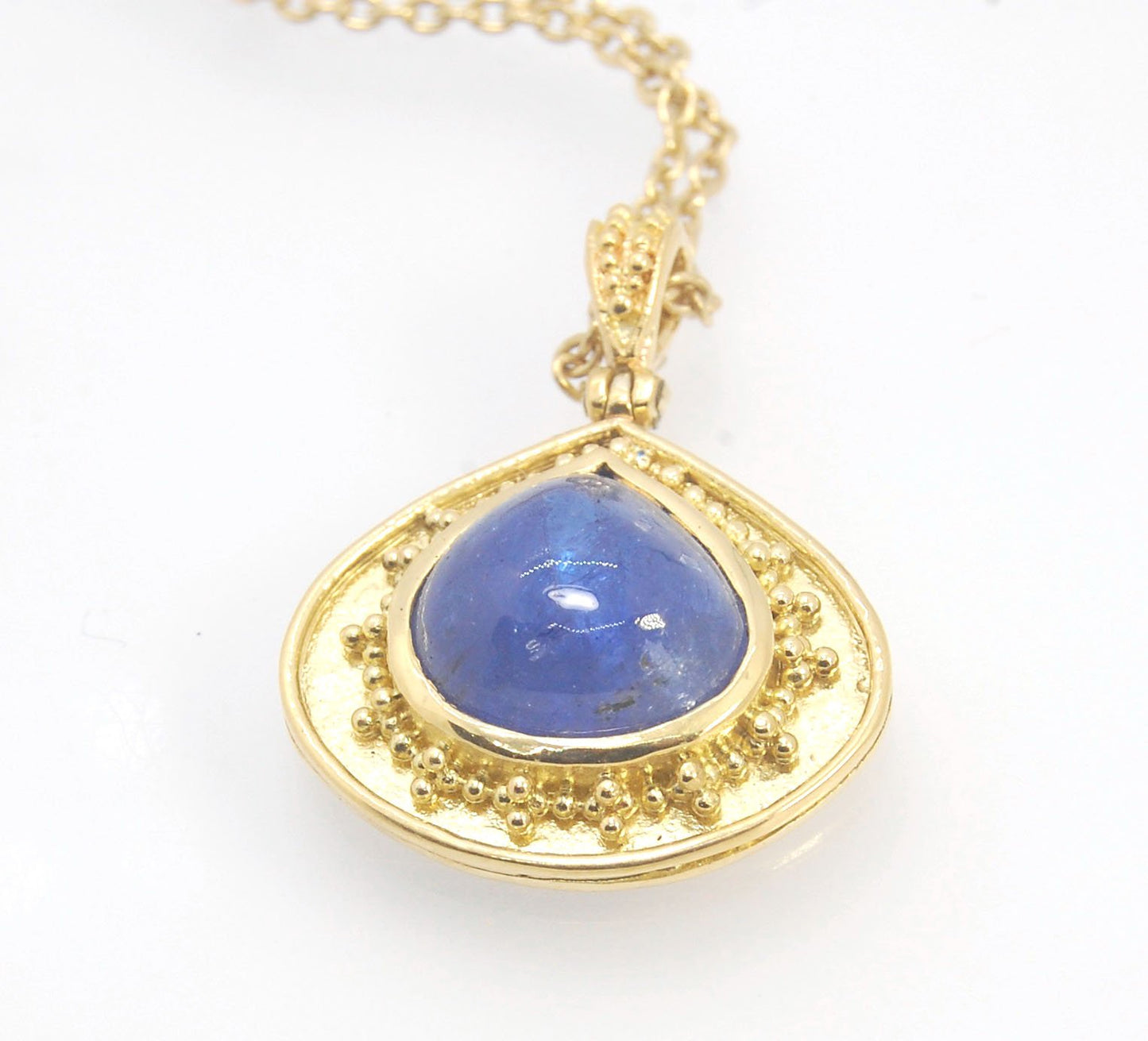 Blue Drop Tanzanite Cabochon 18k Gold Granulation Pendant and 14k 18" Chain This super blue teardrop-shaped Tanzanite is bezel-set in rich 18k gold bezel setting surrounded by 18k gold granulation with a granulated bail that has been riveted on for more m
