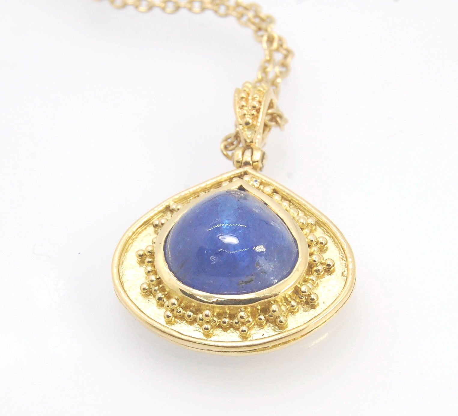 Blue Drop Tanzanite Cabochon 18k Gold Granulation Pendant and 14k 18" Chain This super blue teardrop-shaped Tanzanite is bezel-set in rich 18k gold bezel setting surrounded by 18k gold granulation with a granulated bail that has been riveted on for more m