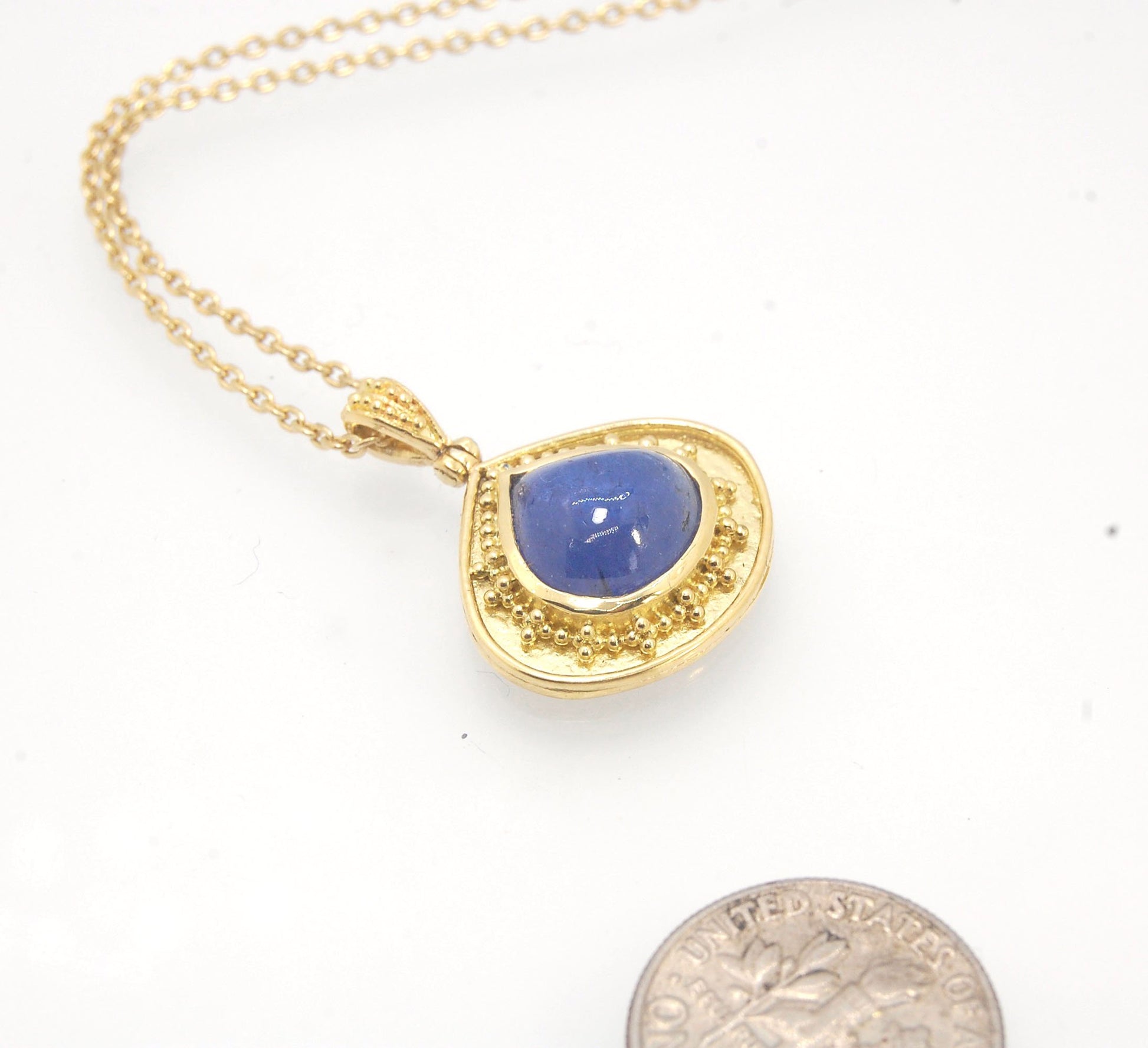 Blue Drop Tanzanite Cabochon 18k Gold Granulation Pendant and 14k 18" Chain This super blue teardrop-shaped Tanzanite is bezel-set in rich 18k gold bezel setting surrounded by 18k gold granulation with a granulated bail that has been riveted on for more m