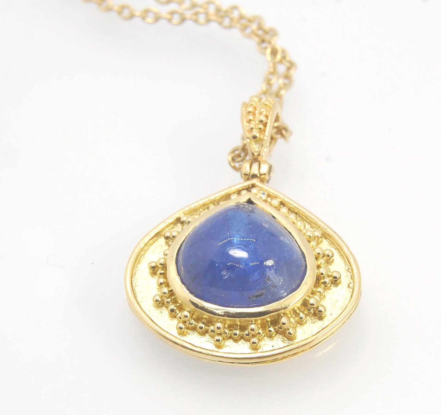 Blue Drop Tanzanite Cabochon 18k Gold Granulation Pendant and 14k 18" Chain This super blue teardrop-shaped Tanzanite is bezel-set in rich 18k gold bezel setting surrounded by 18k gold granulation with a granulated bail that has been riveted on for more m