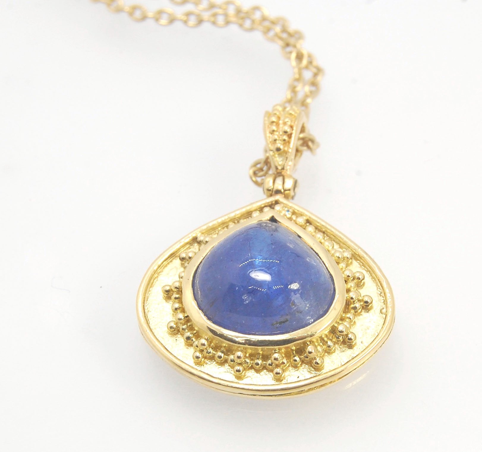 Blue Drop Tanzanite Cabochon 18k Gold Granulation Pendant and 14k 18" Chain This super blue teardrop-shaped Tanzanite is bezel-set in rich 18k gold bezel setting surrounded by 18k gold granulation with a granulated bail that has been riveted on for more m