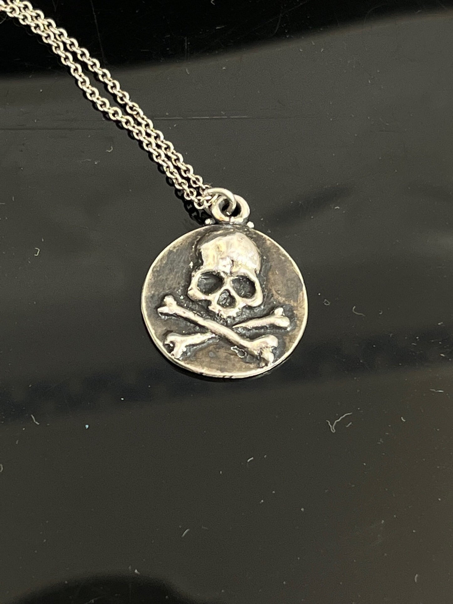 Skullbones Coin Pendant This solid sterling silver Skulbones coin pendant is wax carved by hand and cast using the ancient process of Lost Wax casting. I then made a mold, which I can inject with wax and make wax copies of the Skull and Crossbones Coin an