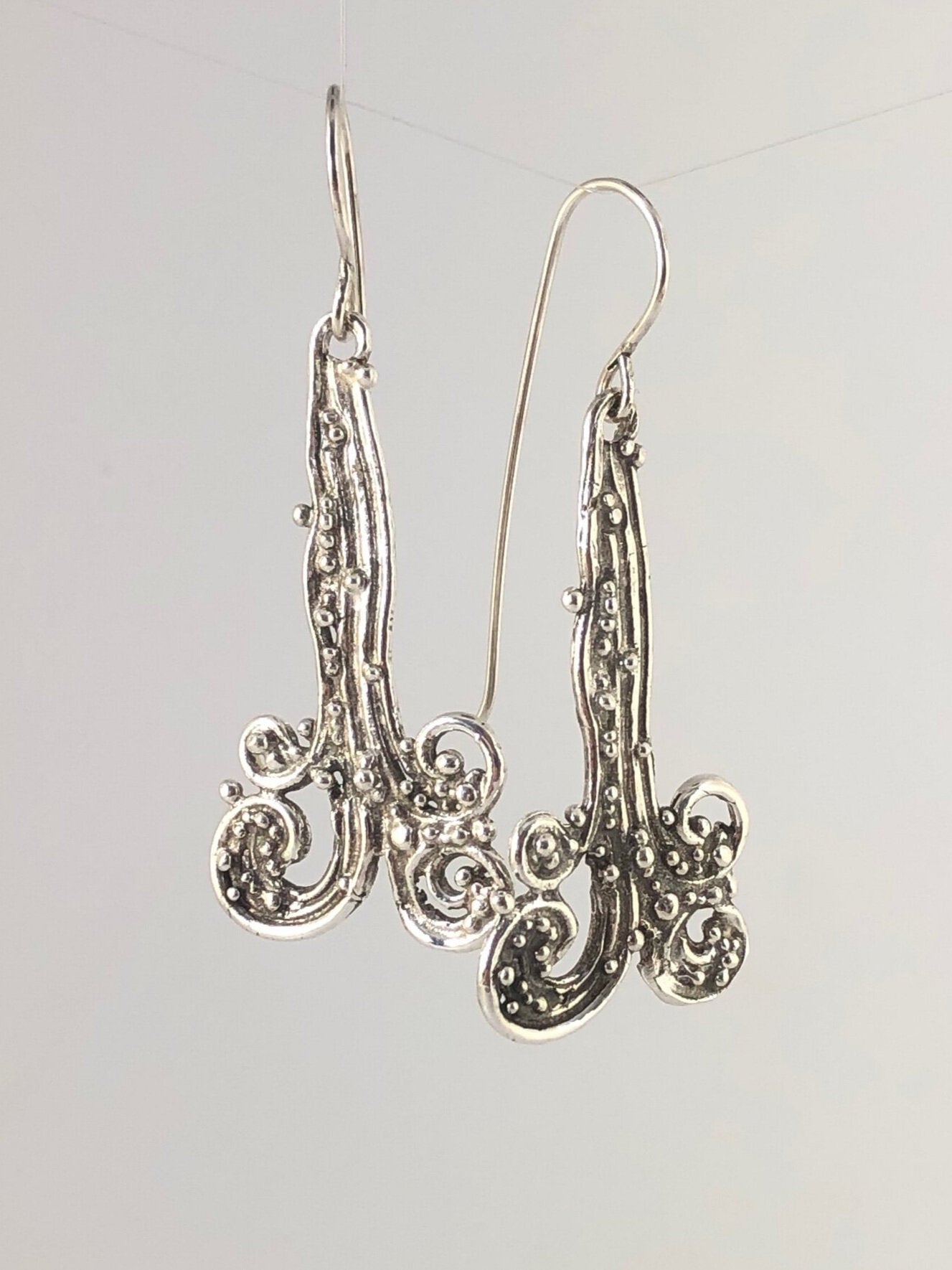 Waterfall Earrings These long Wave Dangles are part of my new work. These are cast versions of my original granulation work, which is then molded for repeat waxes and then cast using the Lost Wax process.These waterfall dangles have a dark patina and are