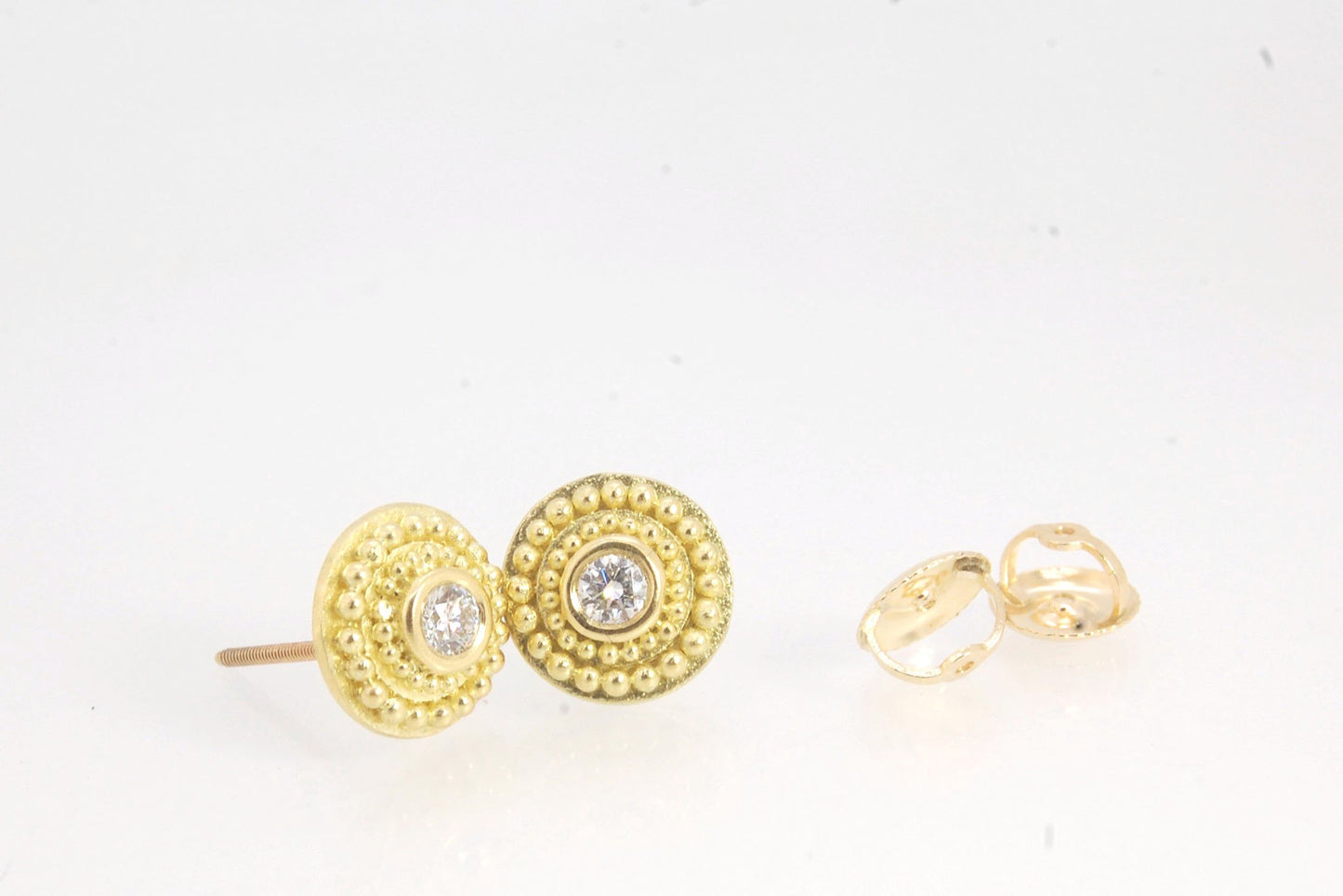 Diamond Disc Post Earrings - 18k Gold Granulation with 14k screw backs These Diamond Disc Stud Earrings are Classically-inspired 18k granulation. With 2 ethically-mined, .10ct , 3mm, Sl1, F+ round diamonds bezel-set in 18k a double ring of 18k gold granul