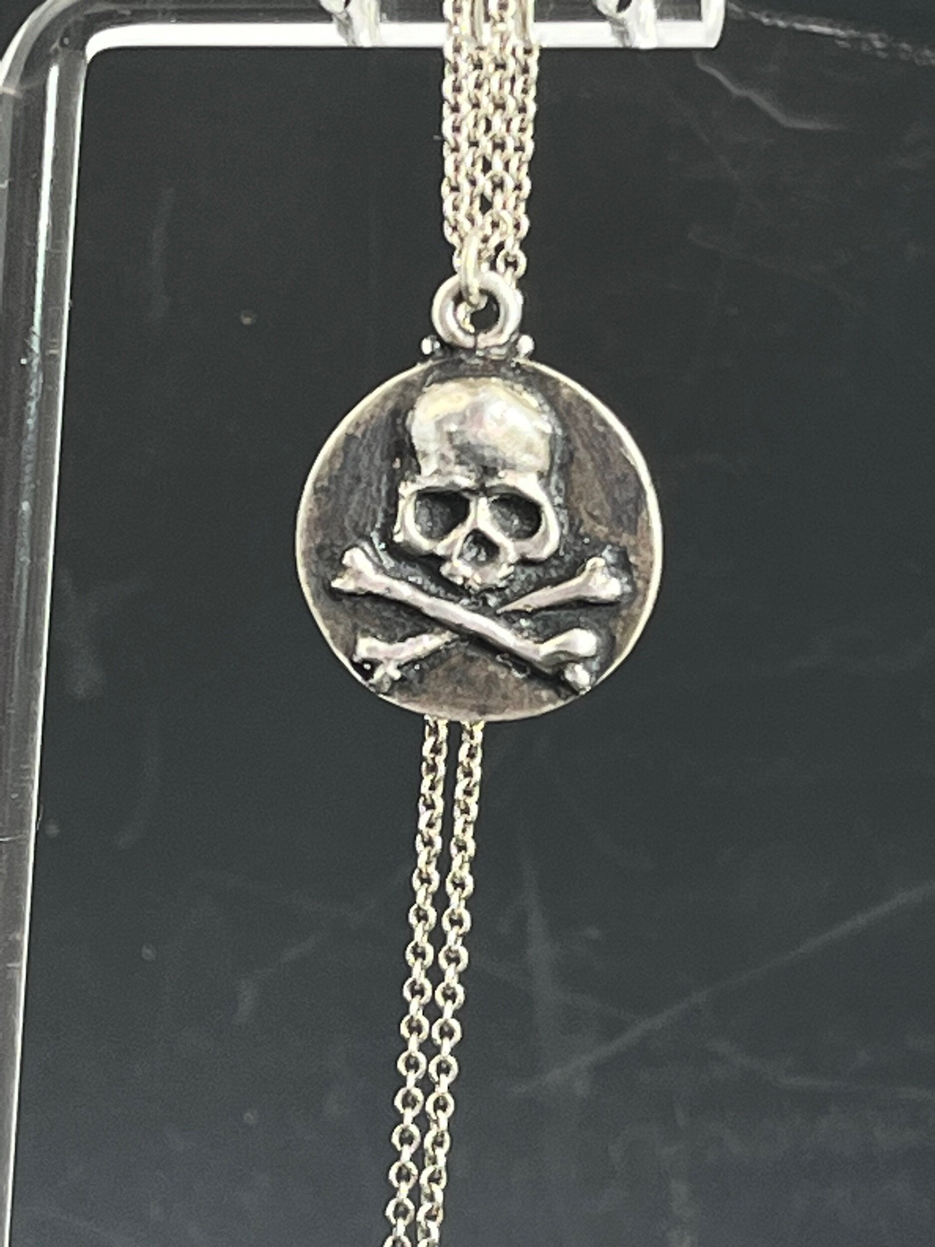 Skullbones Coin Pendant This solid sterling silver Skulbones coin pendant is wax carved by hand and cast using the ancient process of Lost Wax casting. I then made a mold, which I can inject with wax and make wax copies of the Skull and Crossbones Coin an