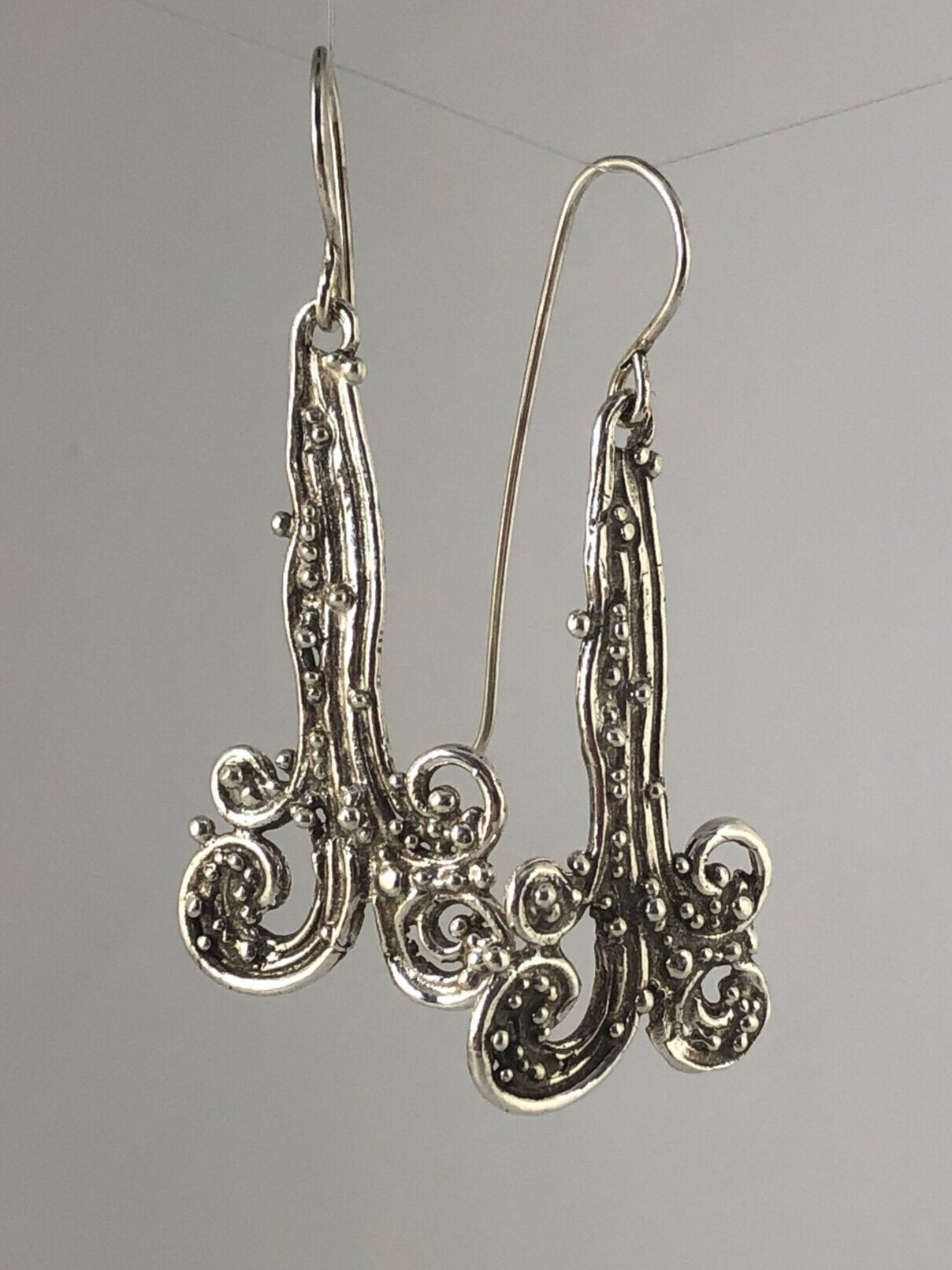 Waterfall Earrings These long Wave Dangles are part of my new work. These are cast versions of my original granulation work, which is then molded for repeat waxes and then cast using the Lost Wax process.These waterfall dangles have a dark patina and are