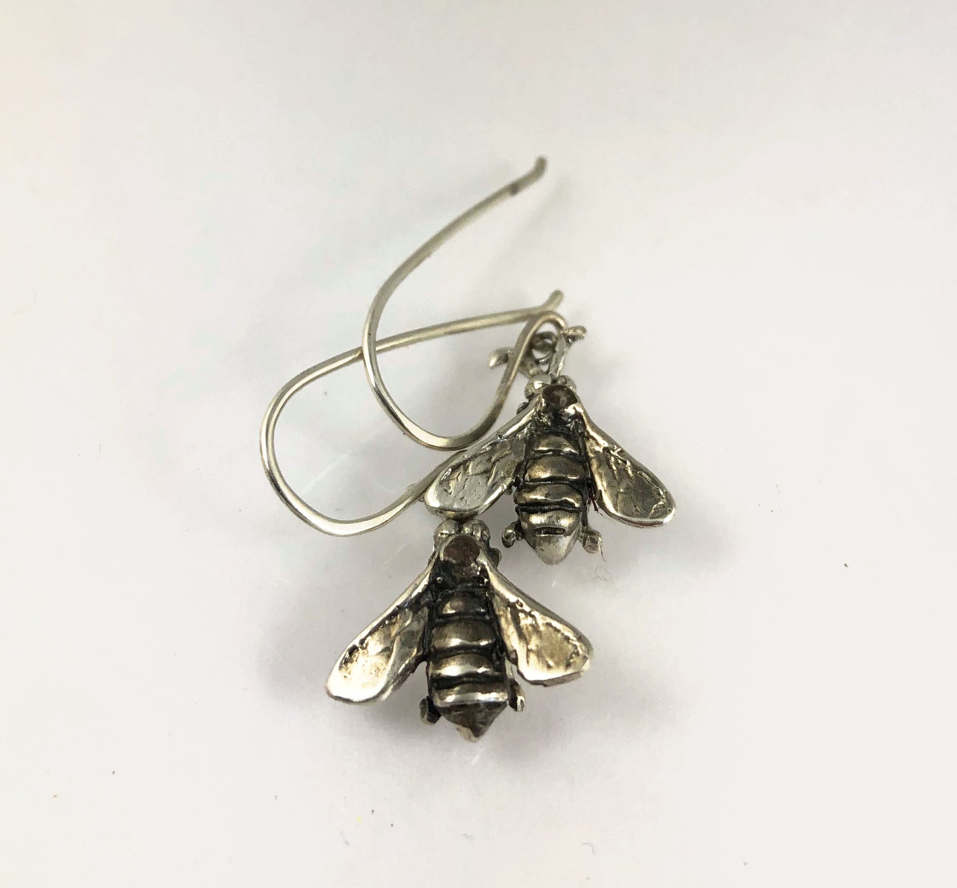 Bee Earrings in Sterling Silver Bee Earrings in Sterling Silver with a French Hook. These bees were so fun to carve!I carved the original bee in wax and then cast it using a lost wax process in sterling. I then made a mold of the sterling bee. Then inject