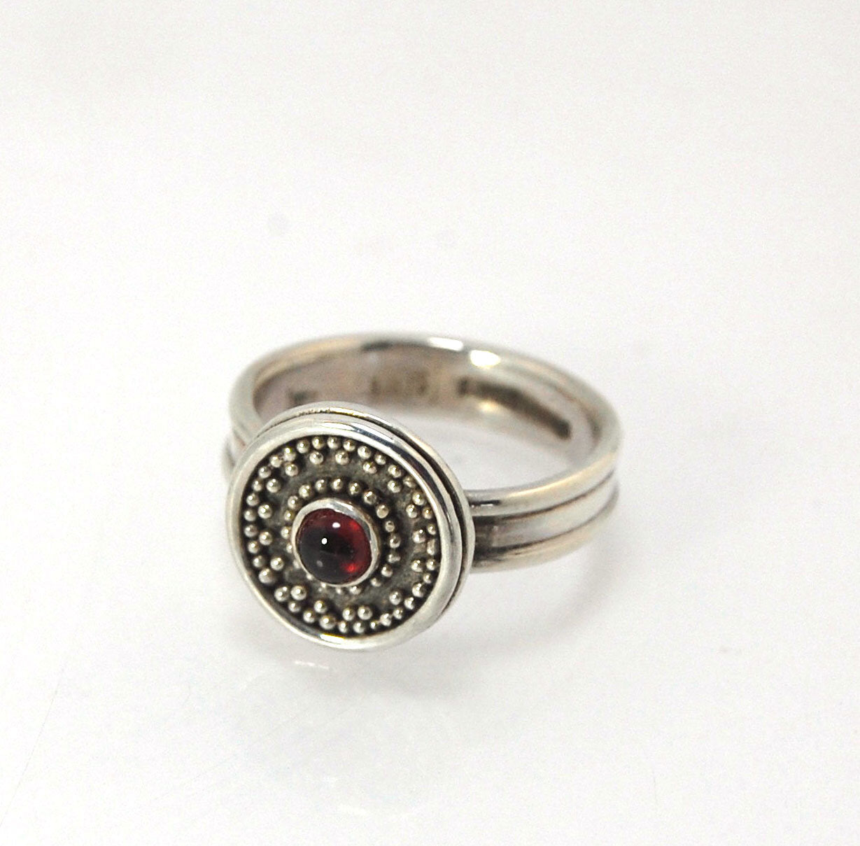 Garnet Granulation Shield Ring - size 7 This Garnet cabochon is bezel-set in a Fine Silver Starburst Pattern with a carved and cast Sterling shank band.Granulation is an ancient fusing process utilized for thousands of years by the Etruscans and Mycenaean