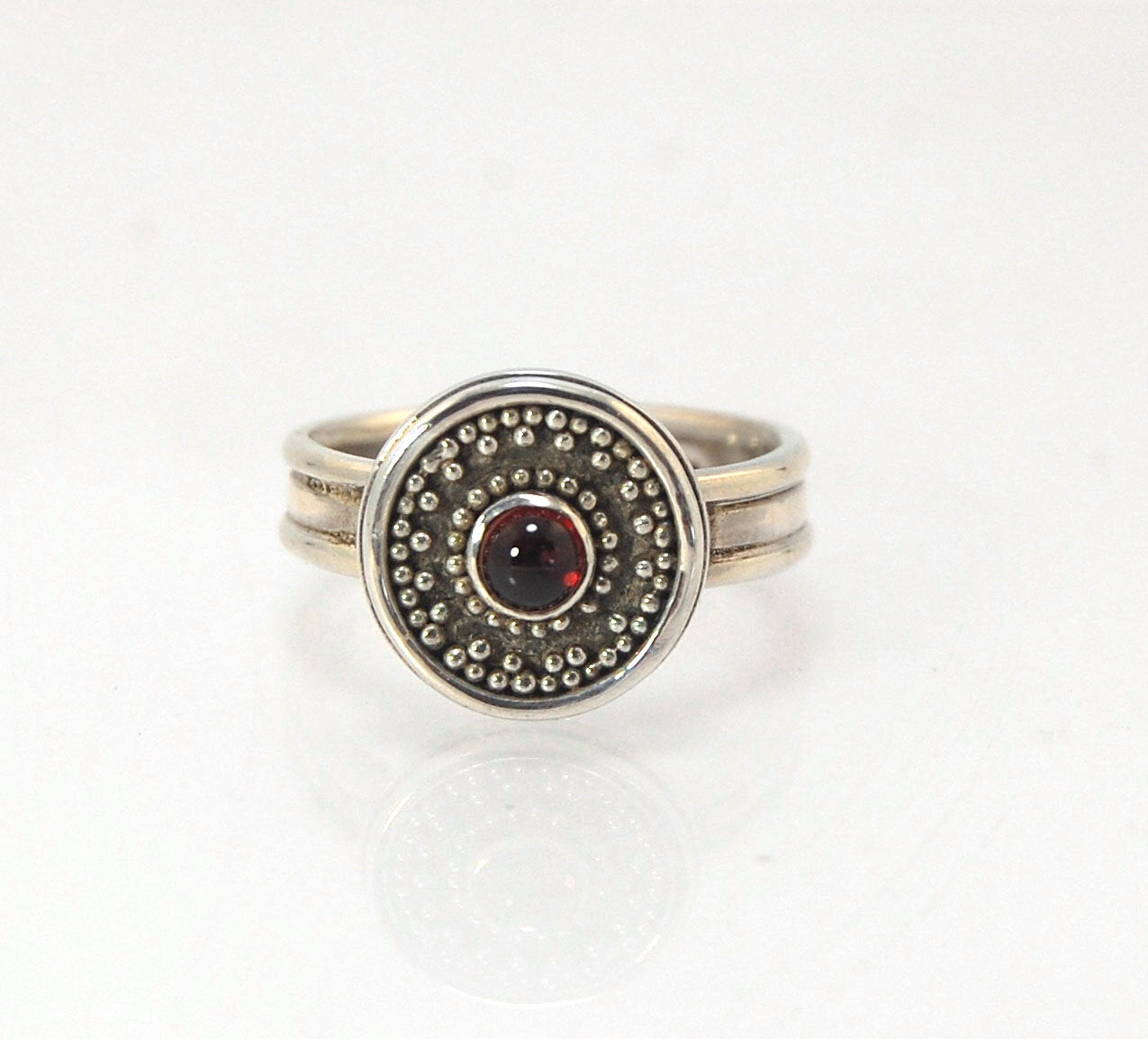 Garnet Granulation Shield Ring - size 7 This Garnet cabochon is bezel-set in a Fine Silver Starburst Pattern with a carved and cast Sterling shank band.Granulation is an ancient fusing process utilized for thousands of years by the Etruscans and Mycenaean