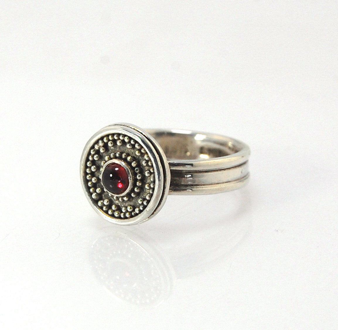 Garnet Granulation Shield Ring - size 7 This Garnet cabochon is bezel-set in a Fine Silver Starburst Pattern with a carved and cast Sterling shank band.Granulation is an ancient fusing process utilized for thousands of years by the Etruscans and Mycenaean