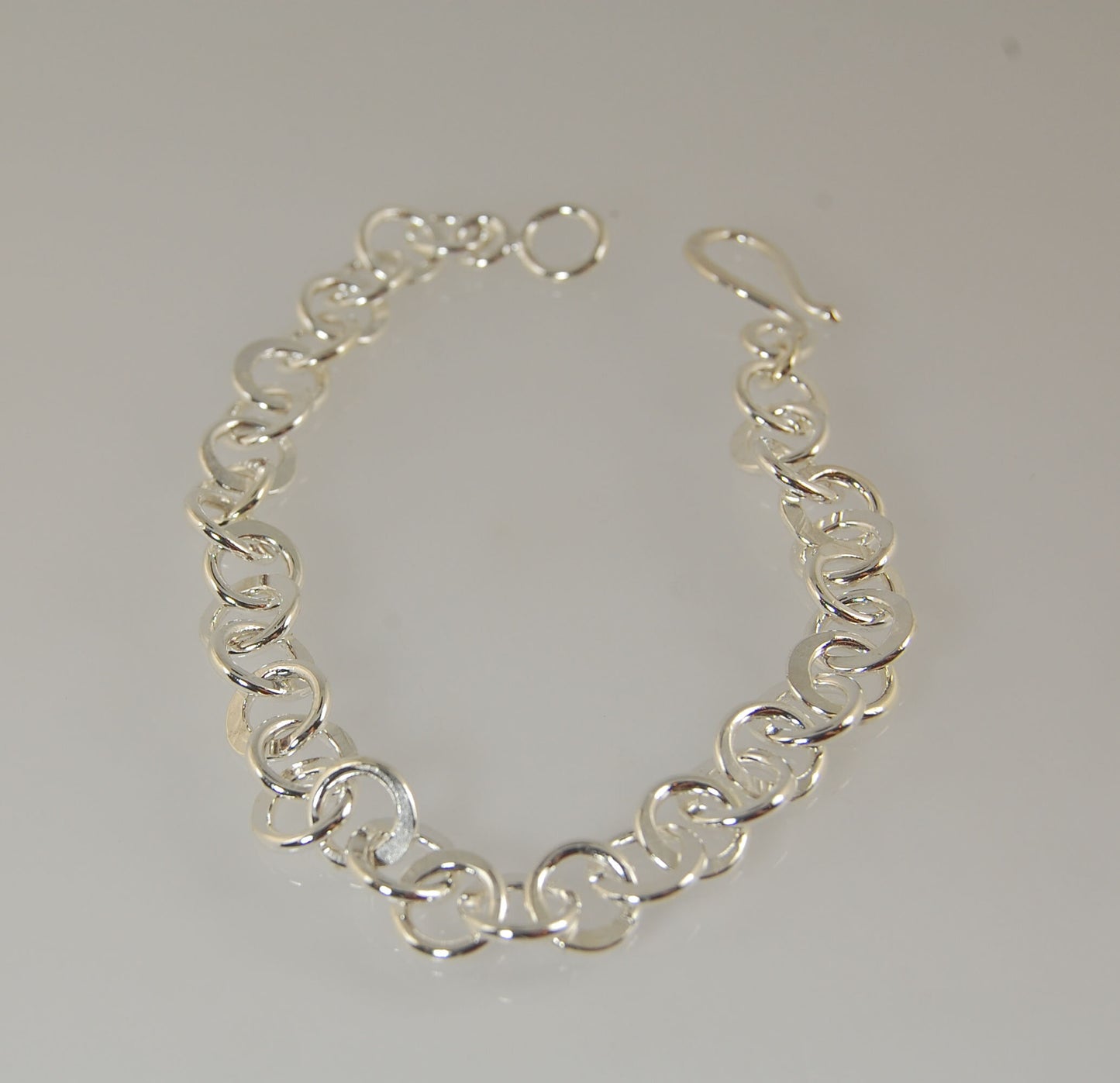 Moonshaped Silver Hammered Link Bracelet These are fun and eye-catching silver bracelets! They have a nice weight without being heavy. Each link is soldered and hammered in a moon pattern for a shimmery look. Each has a forged hook clasp. Each link is for