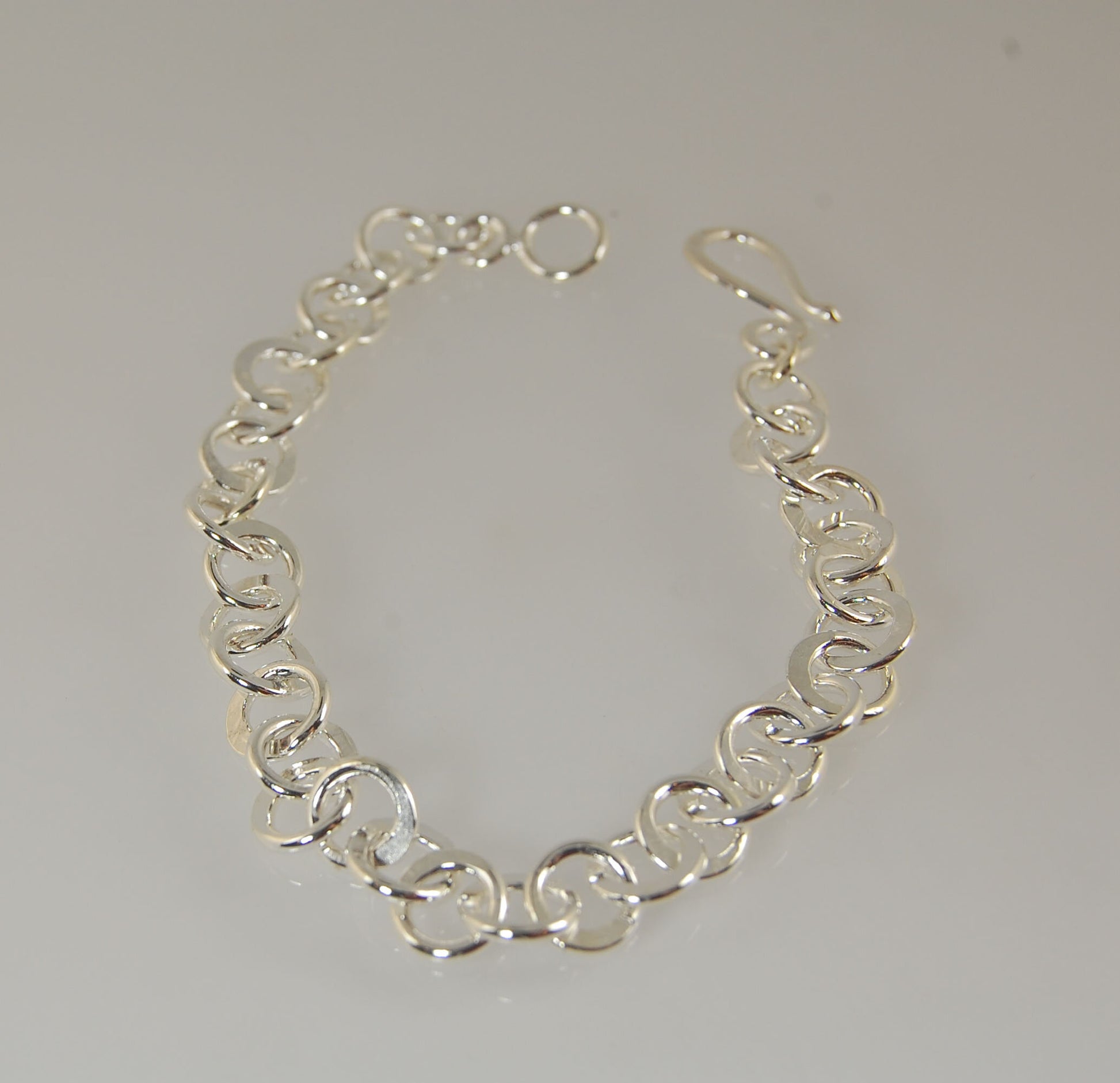 Moonshaped Silver Hammered Link Bracelet These are fun and eye-catching silver bracelets! They have a nice weight without being heavy. Each link is soldered and hammered in a moon pattern for a shimmery look. Each has a forged hook clasp. Each link is for