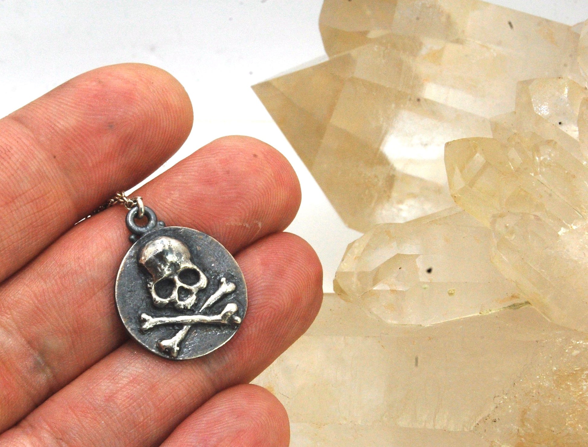 Skullbones Coin Pendant This solid sterling silver Skulbones coin pendant is wax carved by hand and cast using the ancient process of Lost Wax casting. I then made a mold, which I can inject with wax and make wax copies of the Skull and Crossbones Coin an