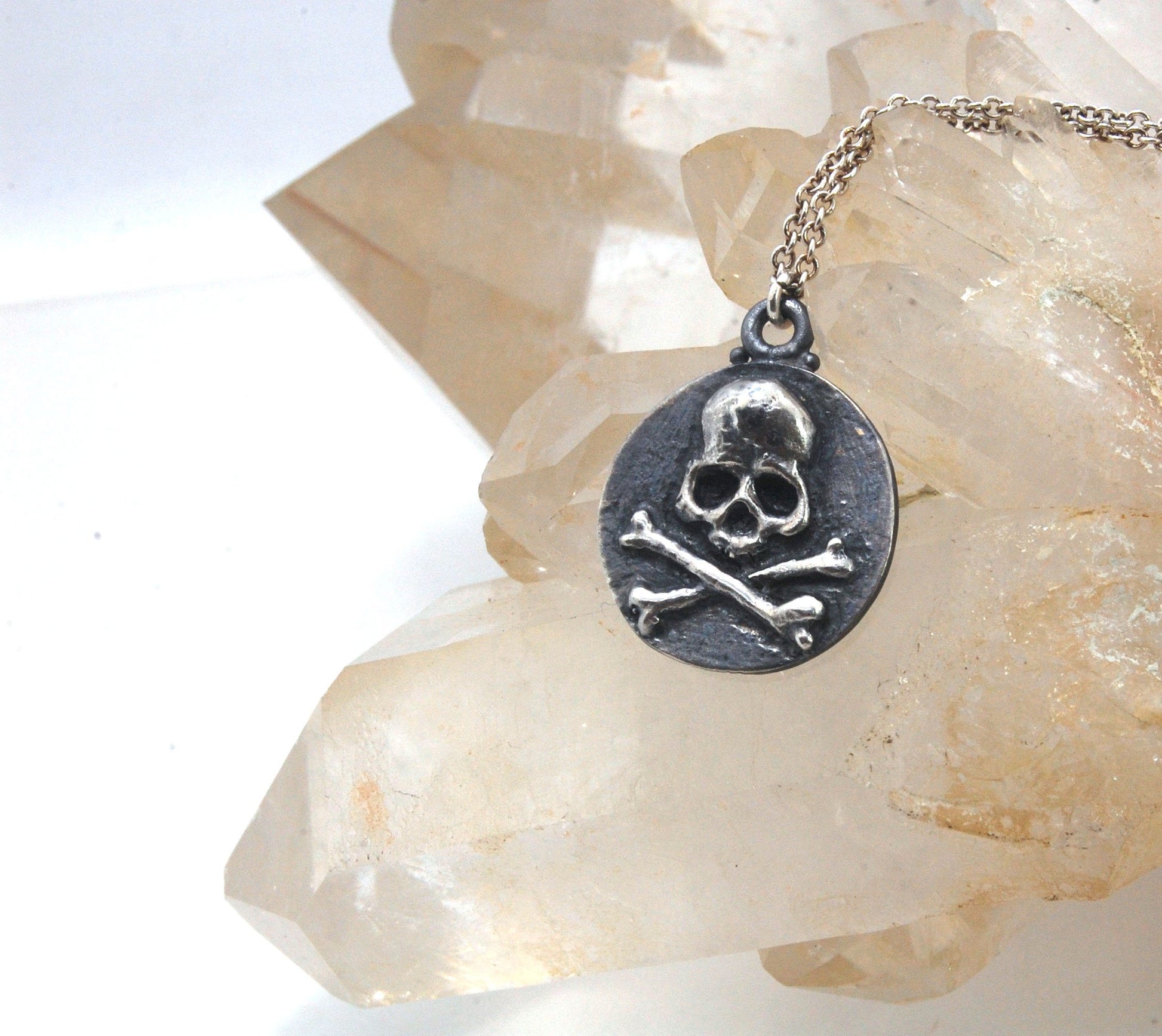 Skullbones Coin Pendant This solid sterling silver Skulbones coin pendant is wax carved by hand and cast using the ancient process of Lost Wax casting. I then made a mold, which I can inject with wax and make wax copies of the Skull and Crossbones Coin an