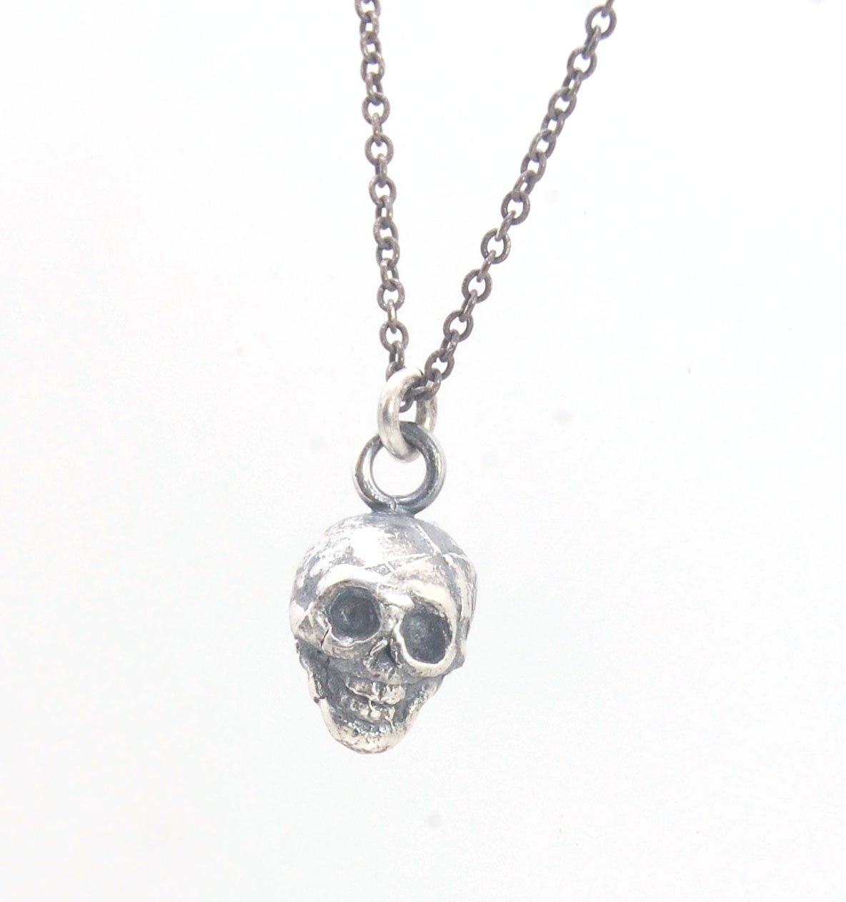 Tiny Skull Charm Pendant This solid sterling silver Skull Pendant is wax carved by hand and cast using the ancient process of Lost Wax casting. I then made a mold, which I can inject with wax and make wax copies of the Jolly Roger Pendant and cast a lot o