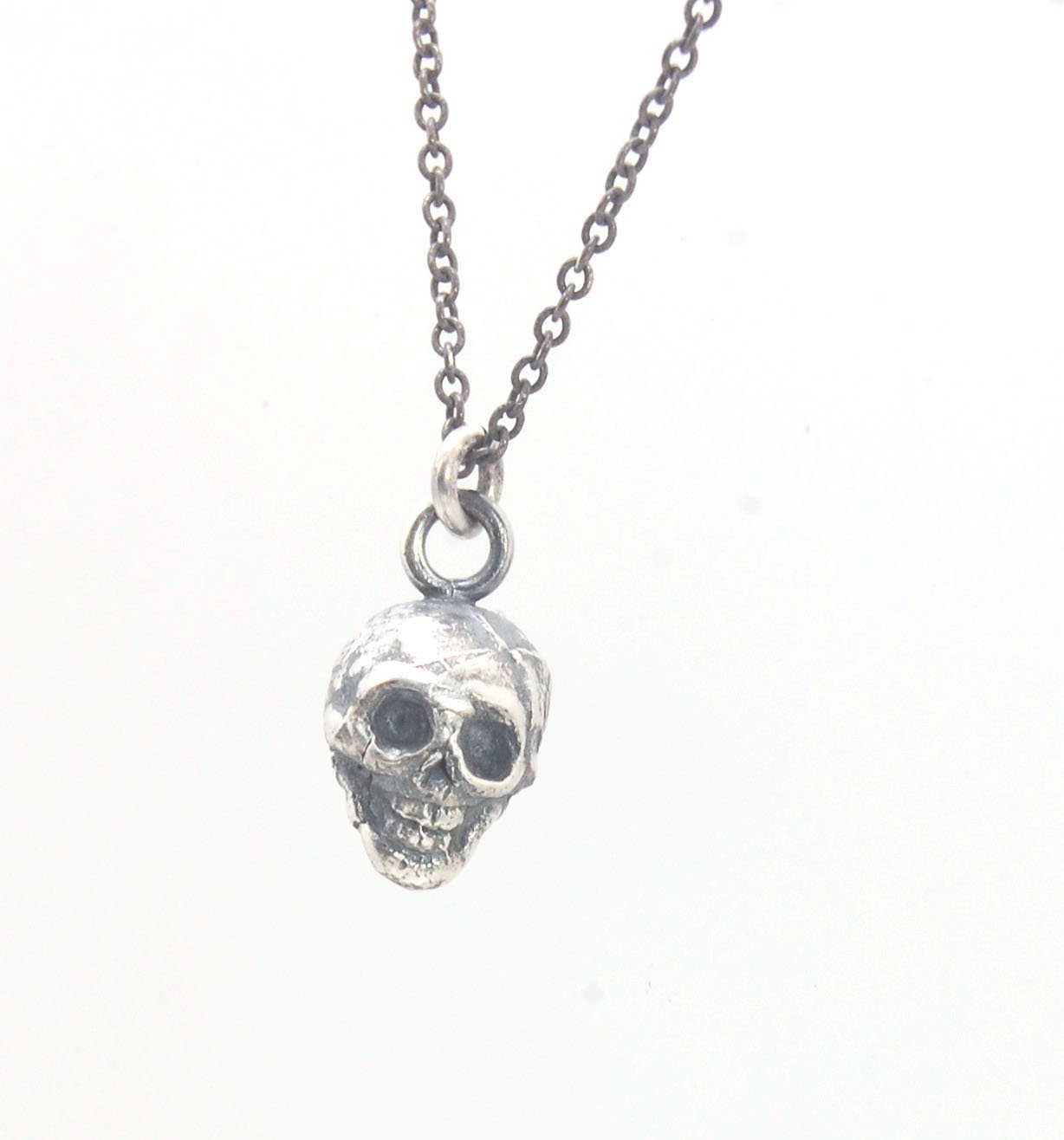 Tiny Skull Charm Pendant This solid sterling silver Skull Pendant is wax carved by hand and cast using the ancient process of Lost Wax casting. I then made a mold, which I can inject with wax and make wax copies of the Jolly Roger Pendant and cast a lot o