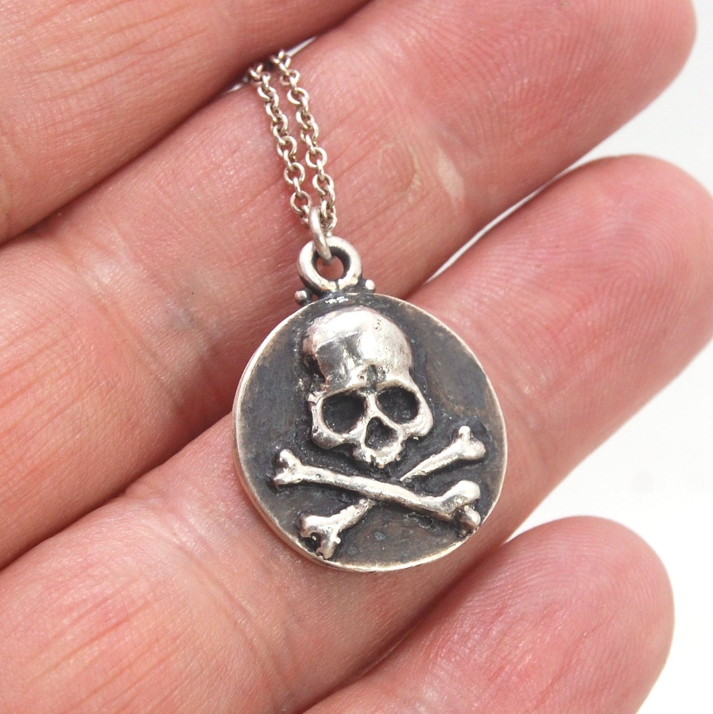 Skullbones Coin Pendant This solid sterling silver Skulbones coin pendant is wax carved by hand and cast using the ancient process of Lost Wax casting. I then made a mold, which I can inject with wax and make wax copies of the Skull and Crossbones Coin an