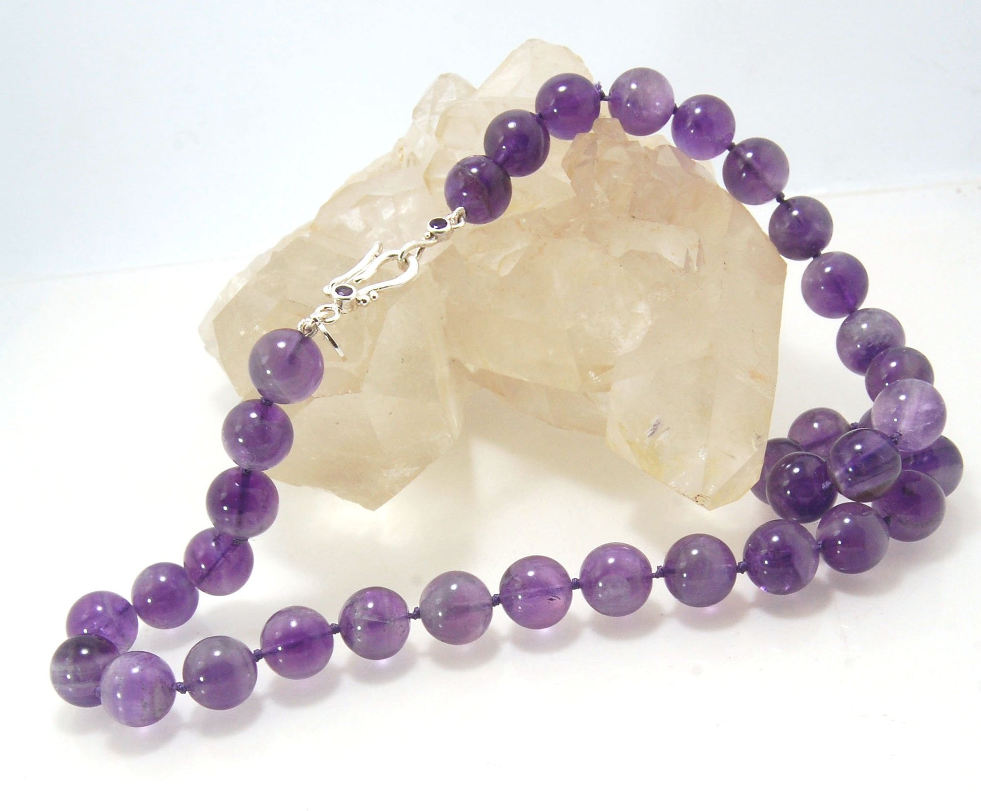 Round Amethyst Gemstone Knotted Strand These lovely round Amethyst Gemstone Beads are a large 11.5mm! These beauties have a nice weight and warmth and are knotted on silk like pearls. I have made a sterling silver two-part clasp with faceted amethysts and