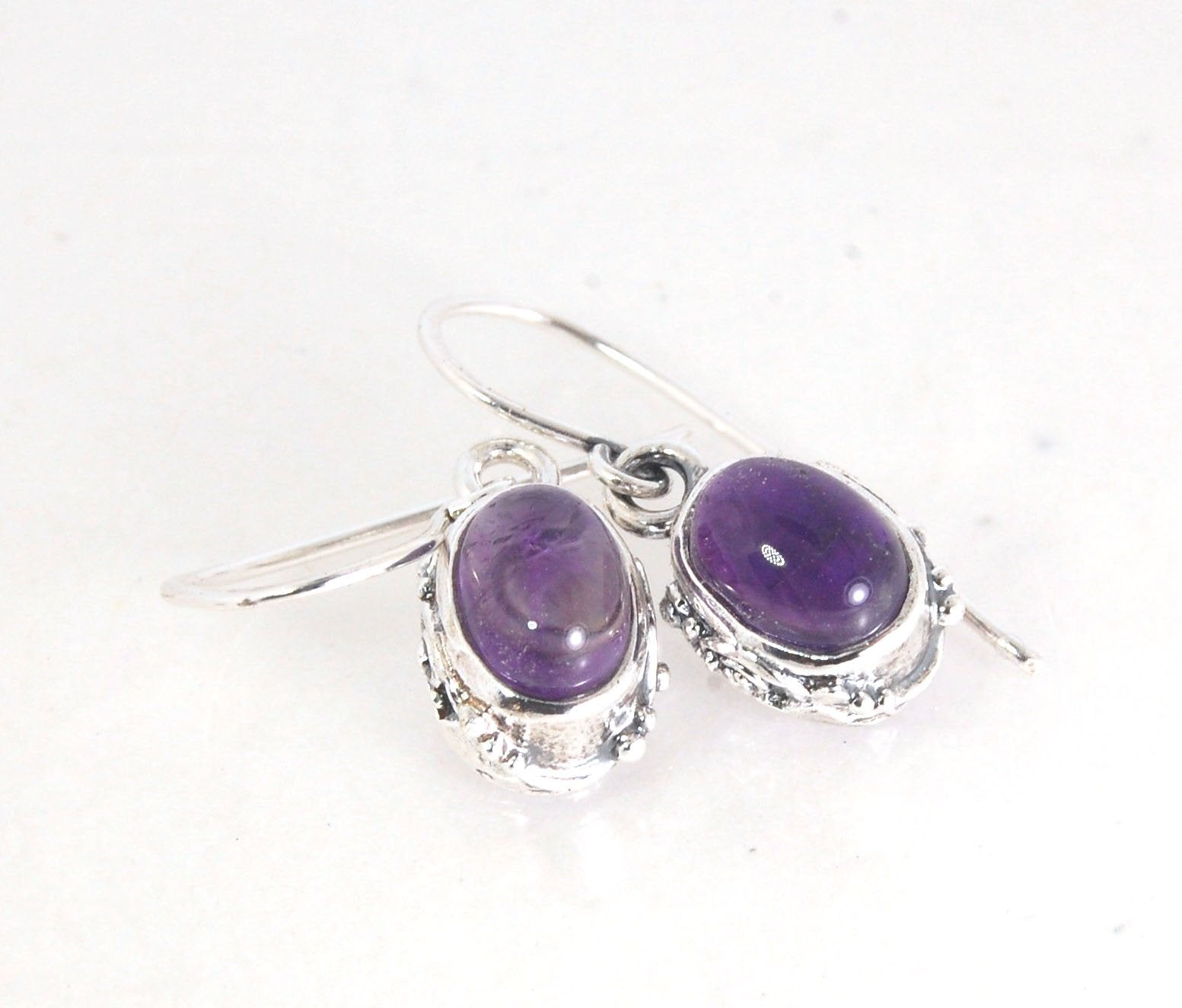 Oval Amethyst Earrings in Swirled silver bezel setting with french hook These are cast in my studio using the ancient technique of lost wax casting, and are molded in wax from an original granulated piece in fine silver. These sweet ovals are reminiscent