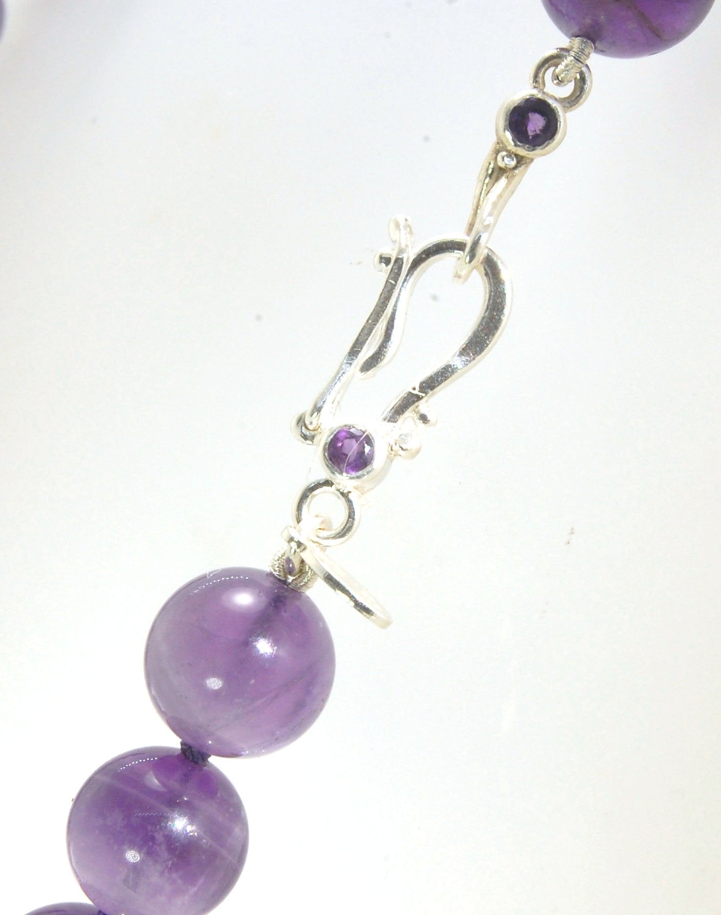 Round Amethyst Gemstone Knotted Strand These lovely round Amethyst Gemstone Beads are a large 11.5mm! These beauties have a nice weight and warmth and are knotted on silk like pearls. I have made a sterling silver two-part clasp with faceted amethysts and