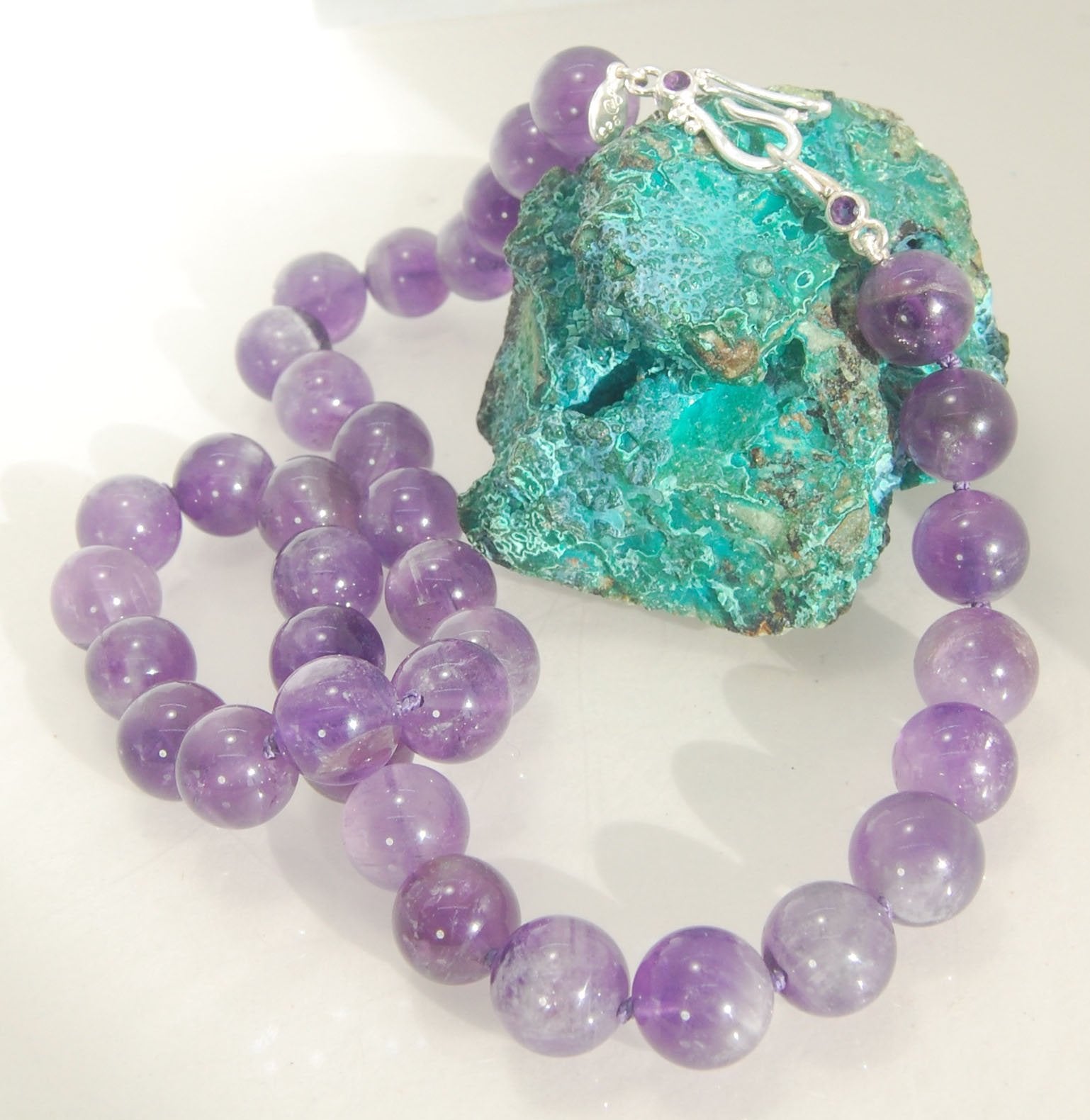 Round Amethyst Gemstone Knotted Strand These lovely round Amethyst Gemstone Beads are a large 11.5mm! These beauties have a nice weight and warmth and are knotted on silk like pearls. I have made a sterling silver two-part clasp with faceted amethysts and