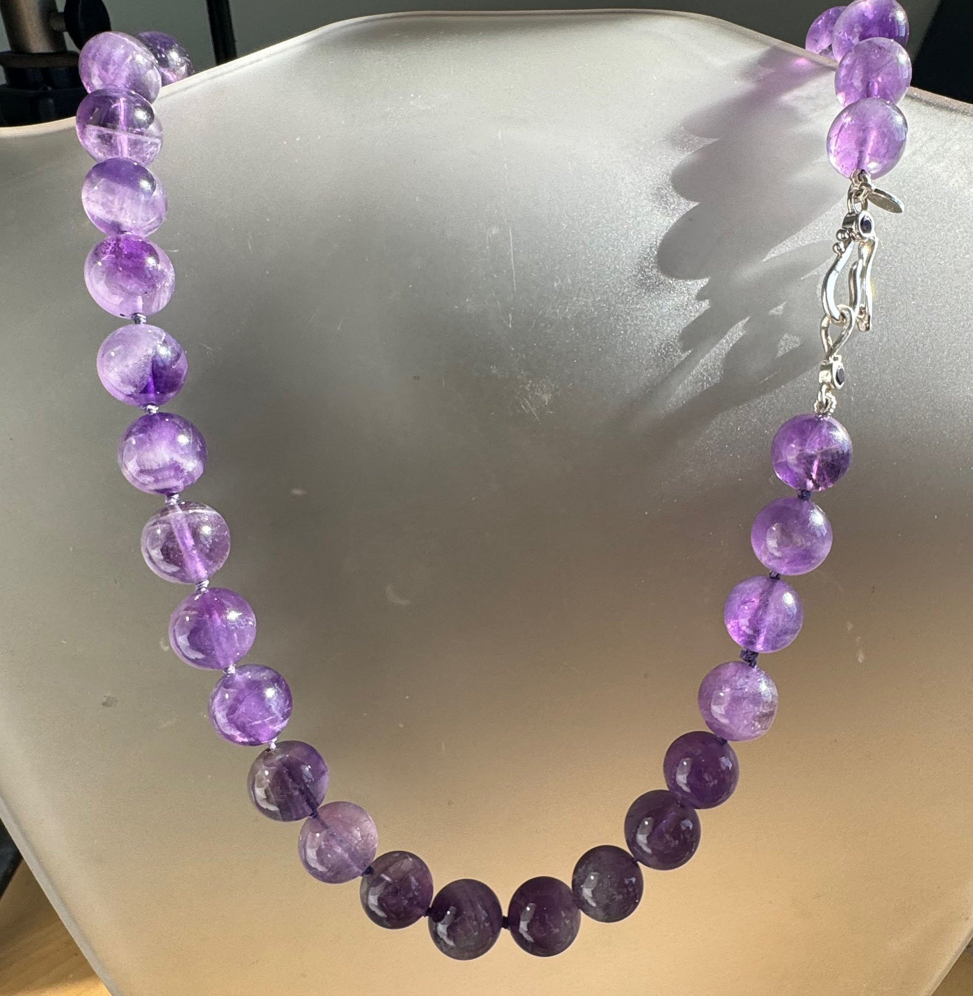 Round Amethyst Gemstone Knotted Strand These lovely round Amethyst Gemstone Beads are a large 11.5mm! These beauties have a nice weight and warmth and are knotted on silk like pearls. I have made a sterling silver two-part clasp with faceted amethysts and