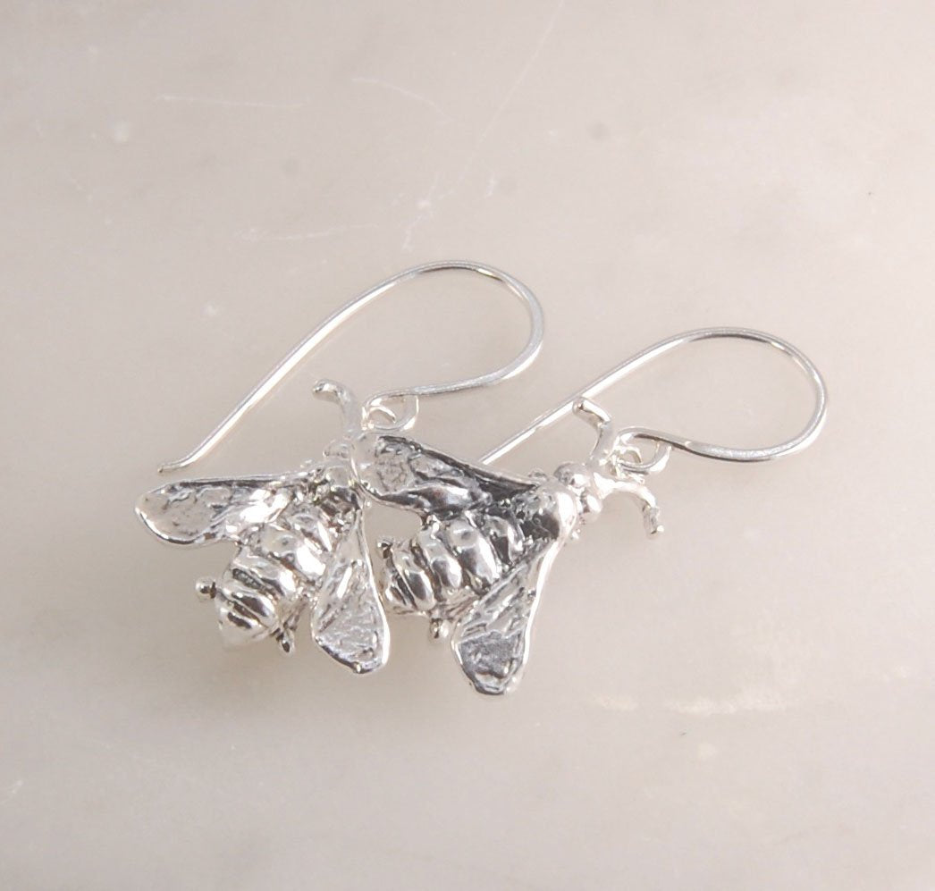 Bee Earrings in Sterling Silver Bee Earrings in Sterling Silver with a French Hook. These bees were so fun to carve!I carved the original bee in wax and then cast it using a lost wax process in sterling. I then made a mold of the sterling bee. Then inject