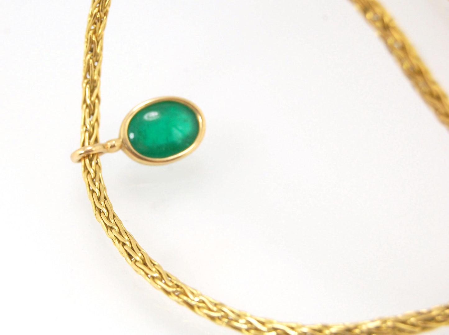 Emerald Cabochon on Handmade Woven 18k gold chain This clear emerald cabochon is bezel-set in 18k gold and suspended from a handmade woven chain of 18k gold in ancient Viking knit. A forged hook clasp finishes this simple and elegant design. Emerald Caboc