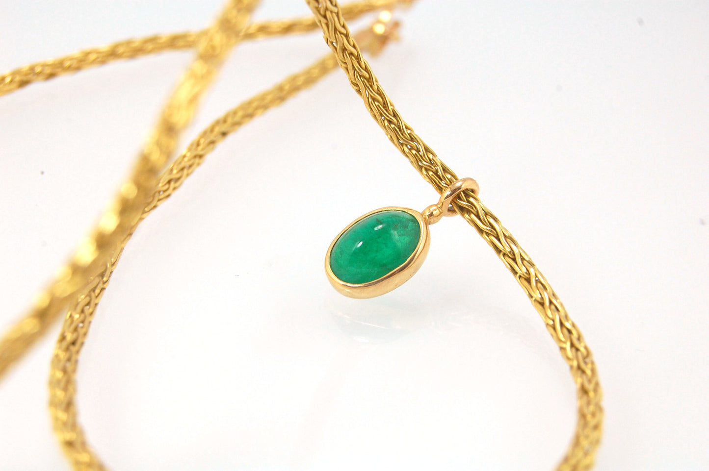 Emerald Cabochon on Handmade Woven 18k gold chain This clear emerald cabochon is bezel-set in 18k gold and suspended from a handmade woven chain of 18k gold in ancient Viking knit. A forged hook clasp finishes this simple and elegant design. Emerald Caboc